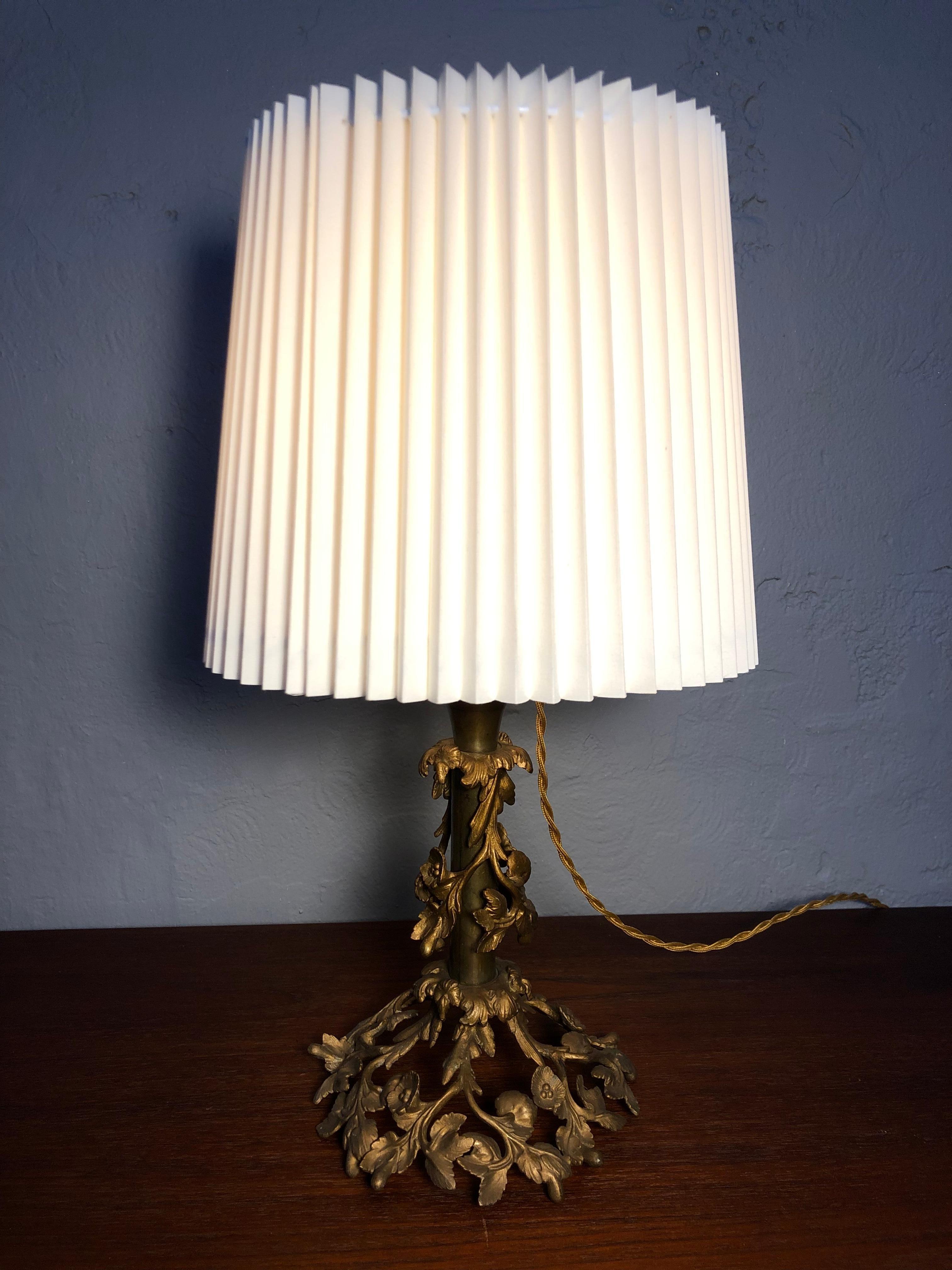 An Antique floral bronze table lamp. 
Richly decorate with a floral design. 
With its original brass and porcelain bulb holder with an on/off switch and brass lampshade holder. 
Rewired with a twisted gold cloth flex. 
Insulated wear the flex