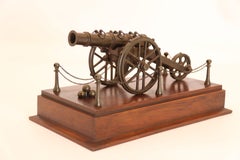 An antique bronze scale model of an 18th century cannon on a hardwood base c1920