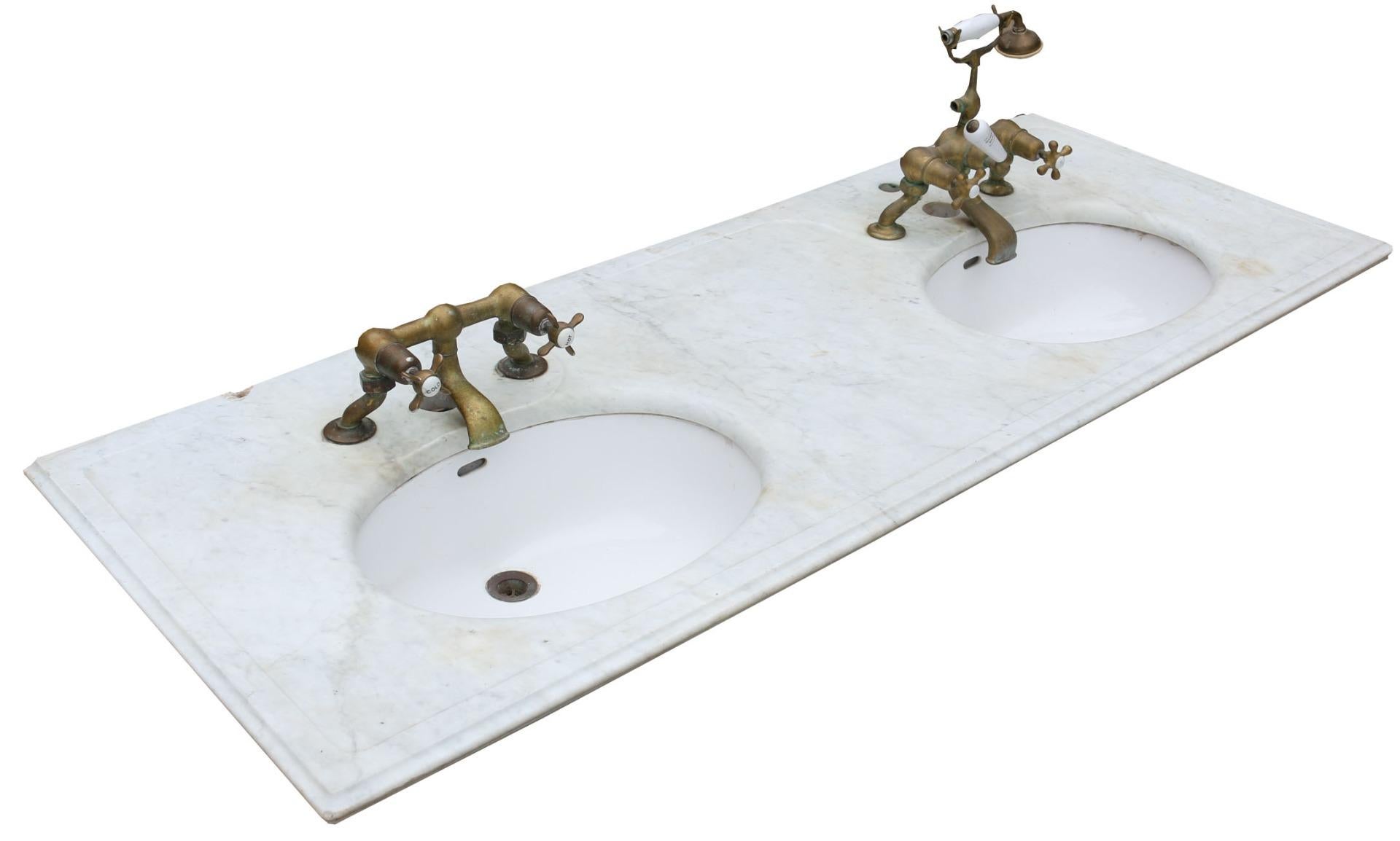 This beautiful double basin is made from a white and grey veined Carrara marble with brass taps and ceramic under-mounted basins.
There are no breaks or cracks.

Taps on the left basin both turn freely.

Taps on the right basin. Left feels seized,