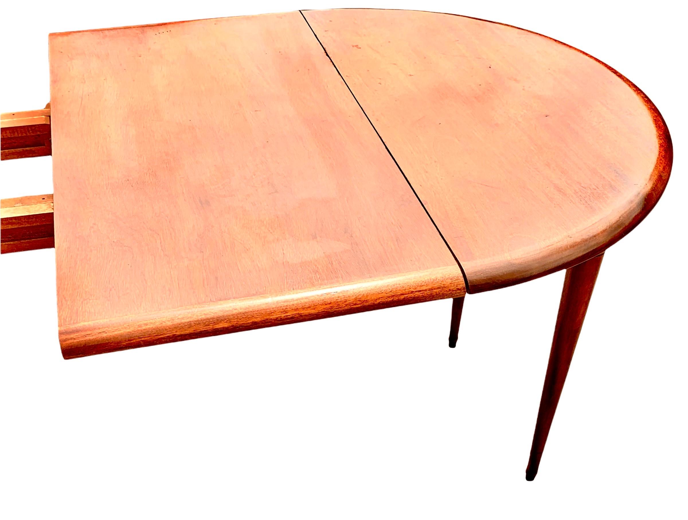 An antique French Louis Philippe carved mahogany round dining table with two 19”extension leaves, having all the original, collapsing wooden supports and center legs, each leg ending with a brass ferrel. There are knock in wooden blocks to tighten