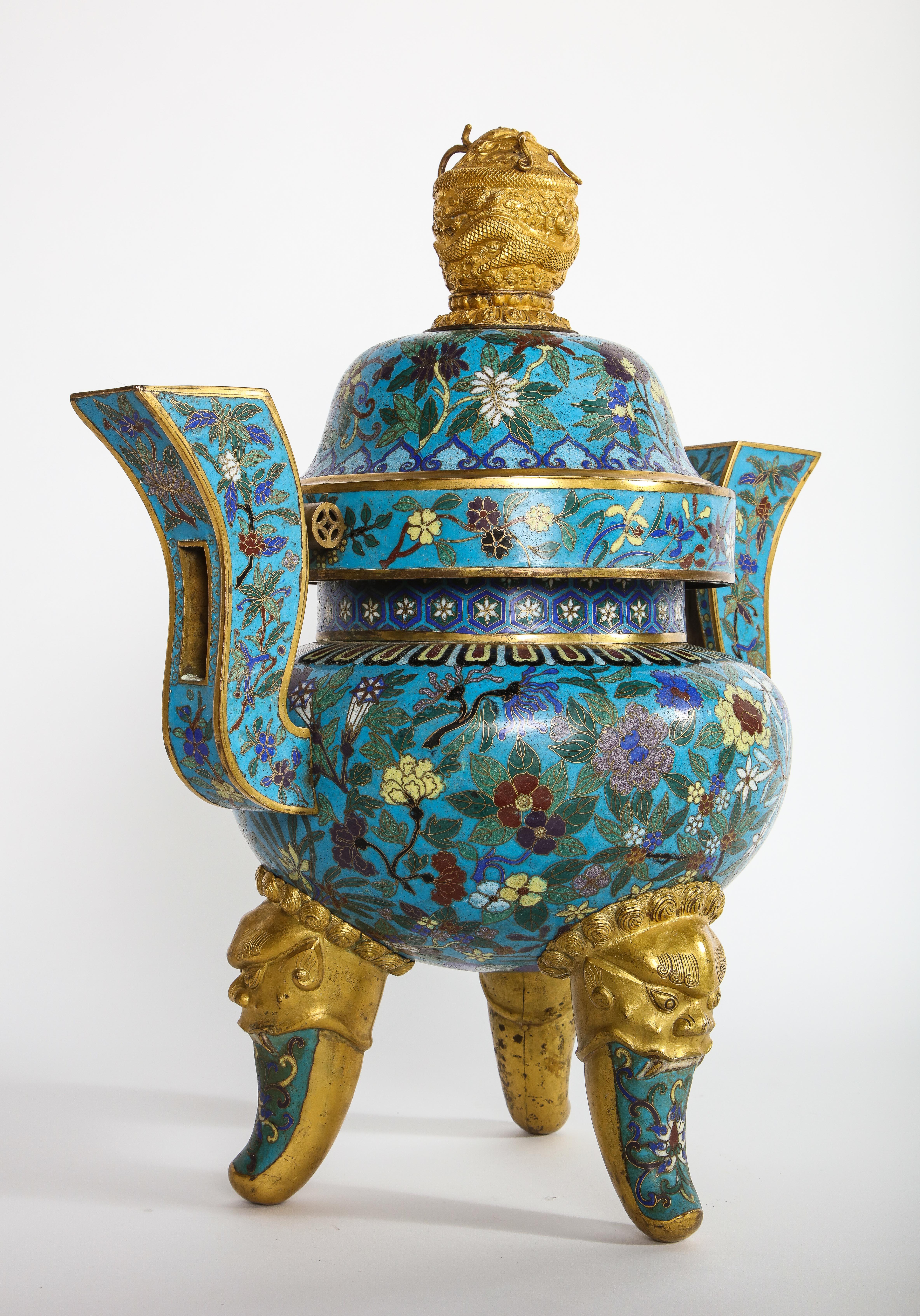 An exceptional antique Chinese cloisonné enamel tripod censor or planter and dragon finial cover. The compressed globular body raised on three cabriole legs issuing from gilt-bronze foo-dog masks and decorated with lotus scroll bearing blossoms