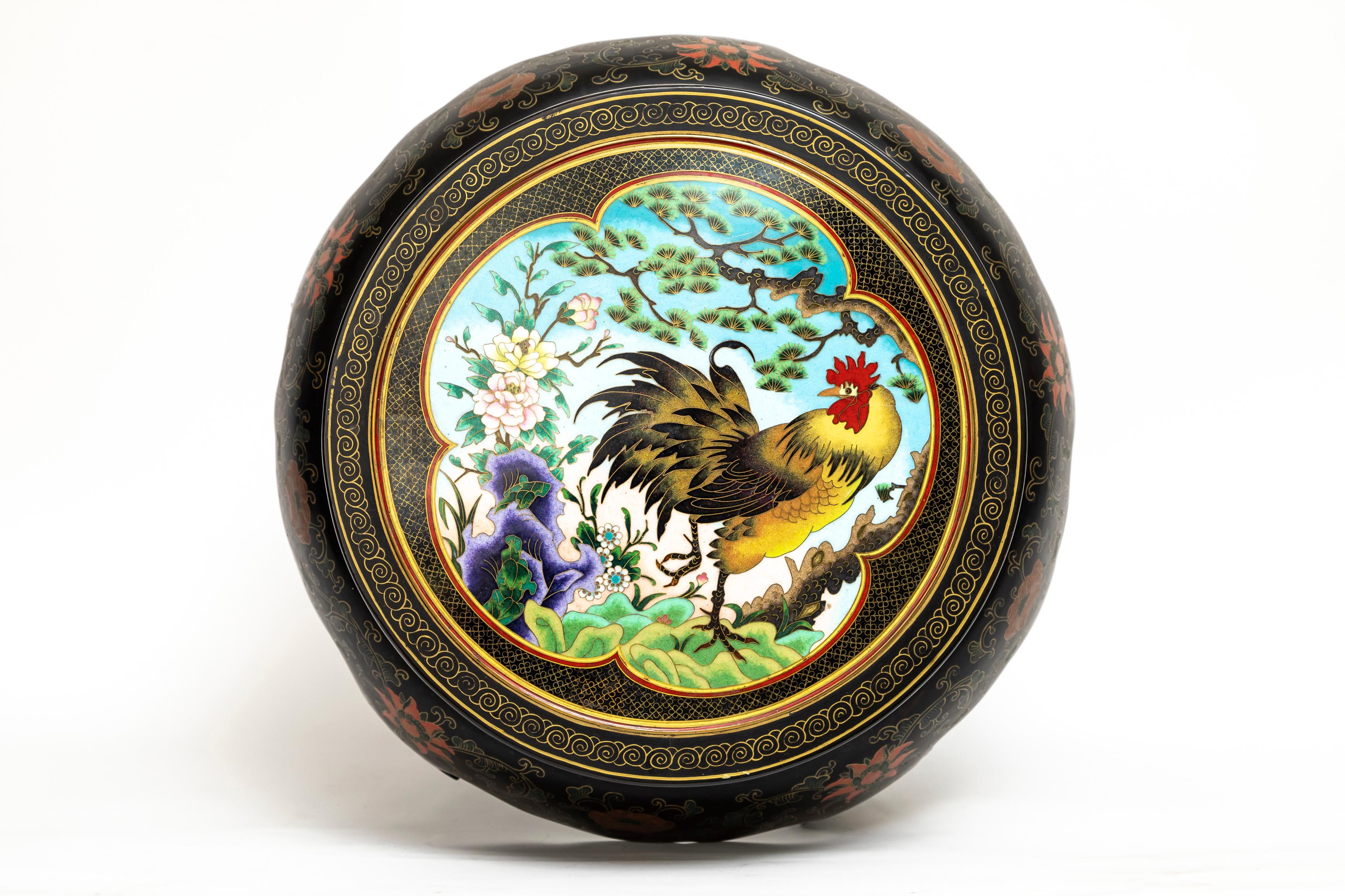 Ancien piédestal/support chinois cloisonné avec plateau incrusté de coqs cloisonnés.  La partie supérieure présente un panneau circulaire cloisonné dans un cadre en bois légèrement en retrait. Le panneau cloisonné présente un motif central