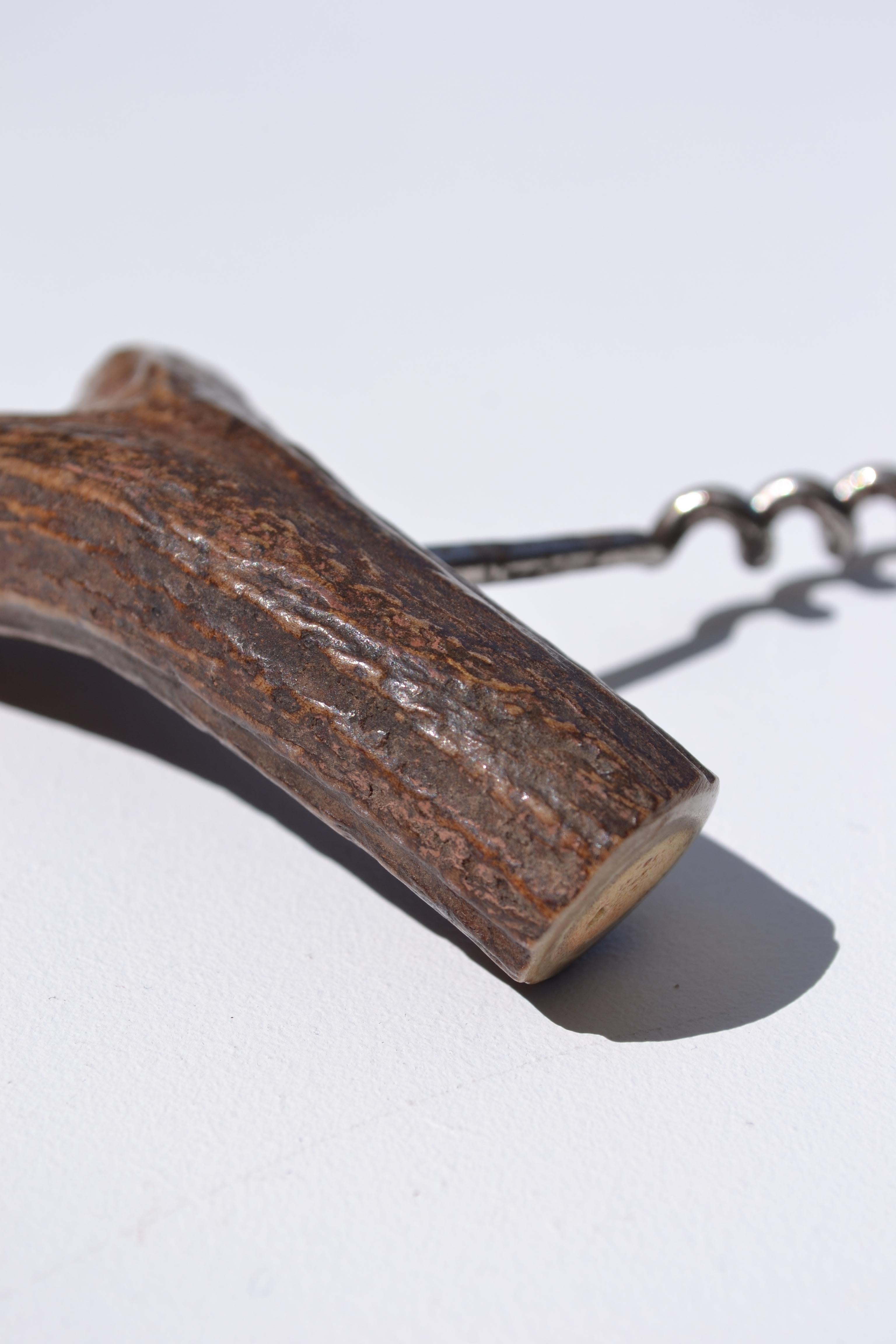 Tire-bouchon ancien fabriqué à partir d'un fragment de bois de cerf, illustrant l'artisanat français du début du XXe siècle. Cette pièce unique se distingue par sa superbe patine, ajoutant une touche d'authenticité et un charme intemporel. Parfait