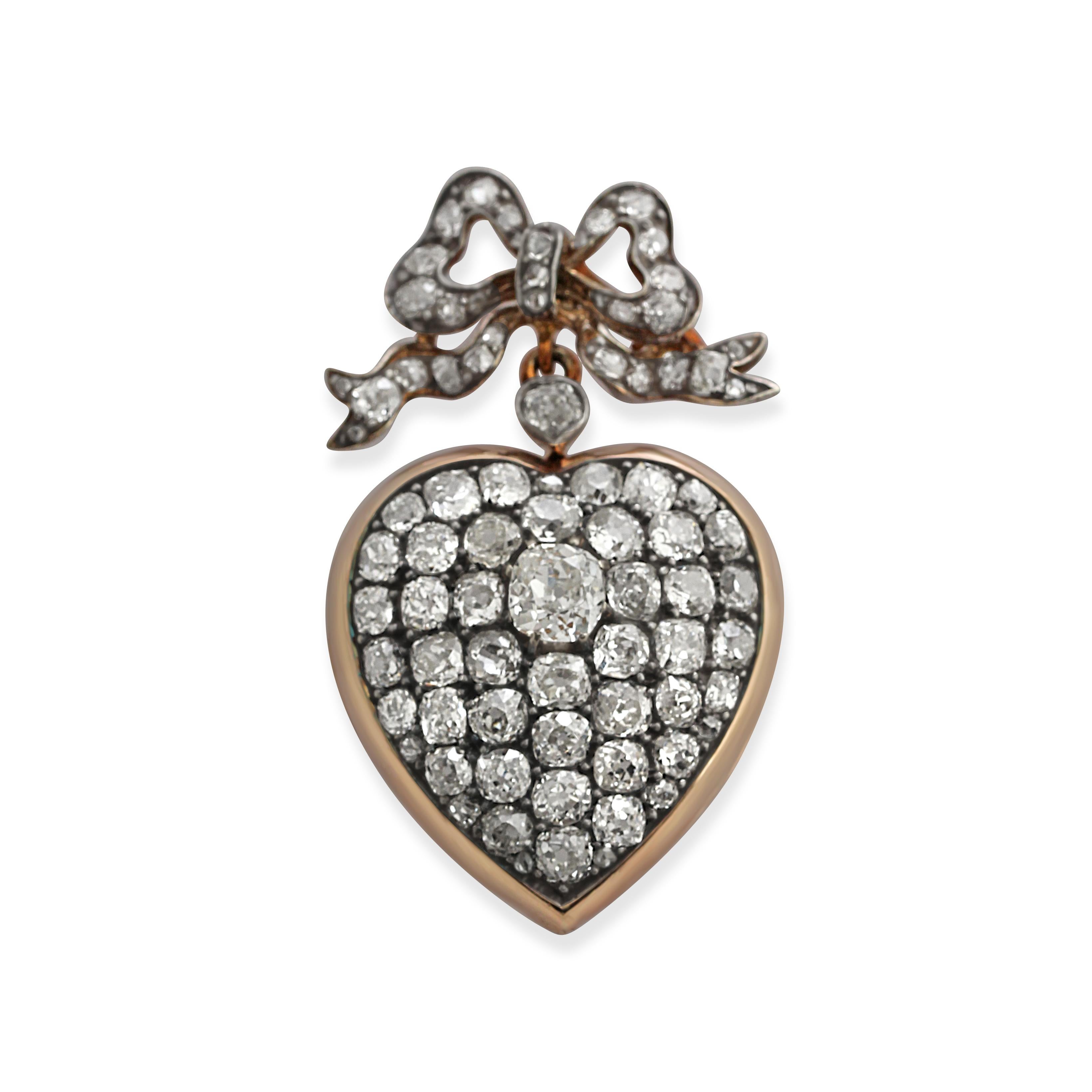 A stunning antique diamond pendant. Crafted from silver mounted on top of gold and set with old and rose-cut diamonds in an elegant heart shape with a bow at the hook. Length = 4.8cm. Weight = 19.30gr.
