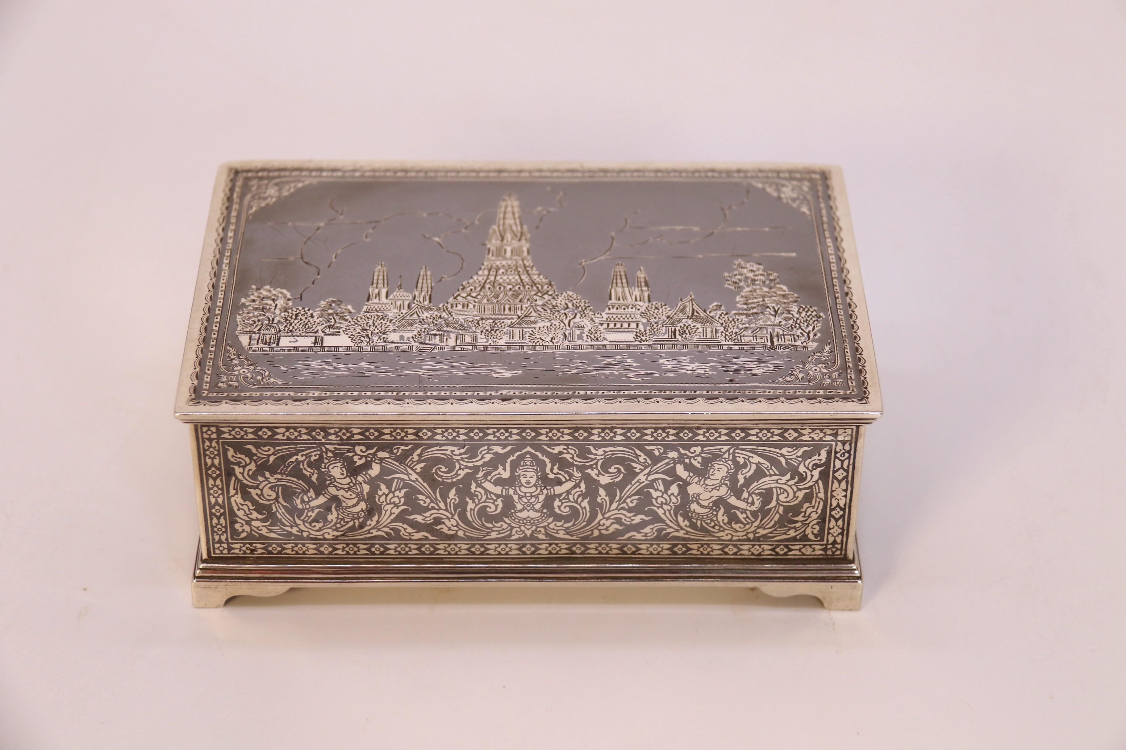 
Cette boîte en argent très intéressante et décorative a été fabriquée au Siam, aujourd'hui la Thaïlande, vers 1920. Il est fabriqué en argent massif de haute qualité (testé) et est magnifiquement décoré d'un travail de niellage qui est une