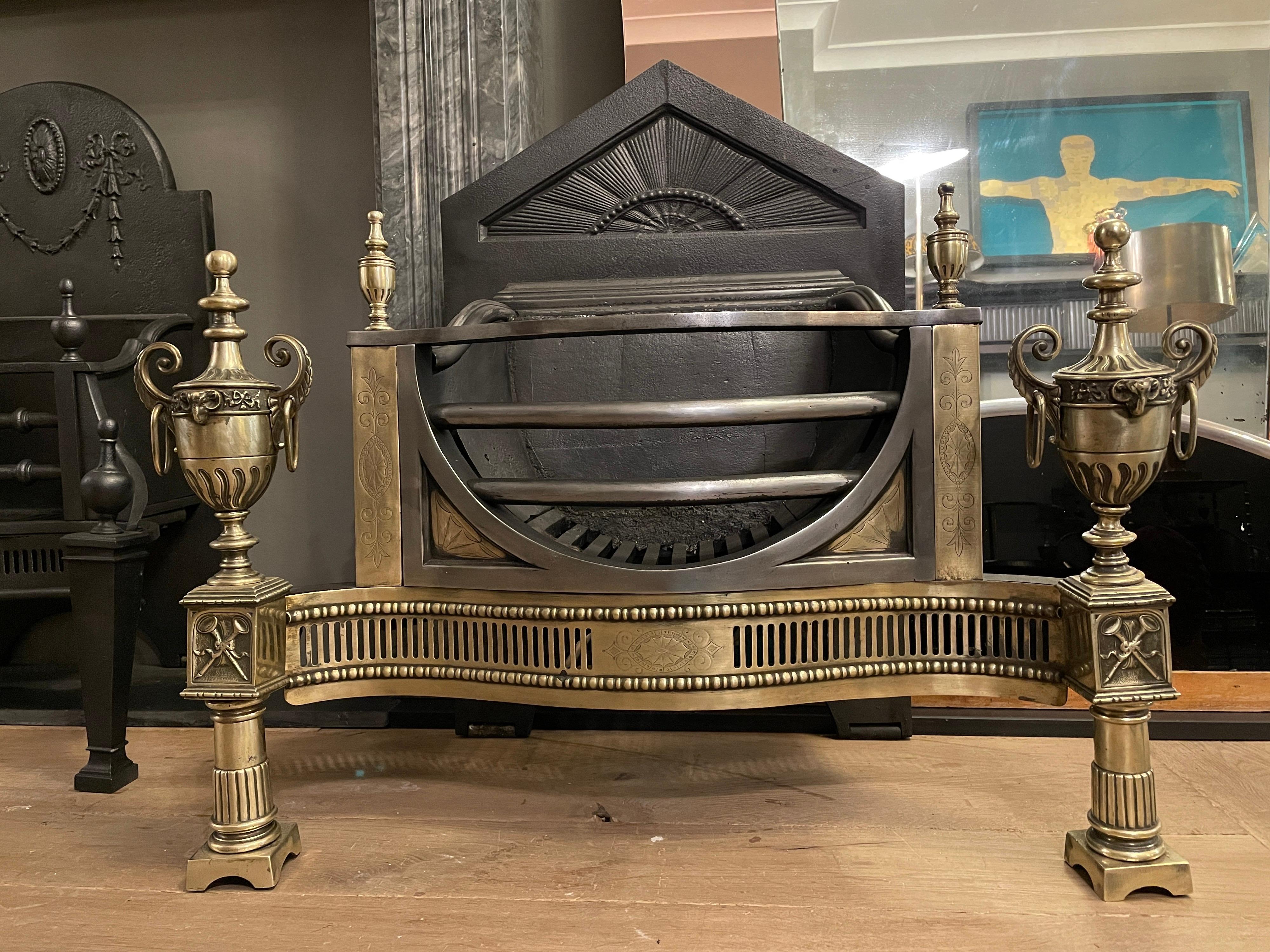A large and decorative 19th century fire grate. The semi circular bowed steel bars flanked by brass pillars engraved and caped with finials. The front supports of reeded columns having square capitals with panelled tied flutes supporting large urns