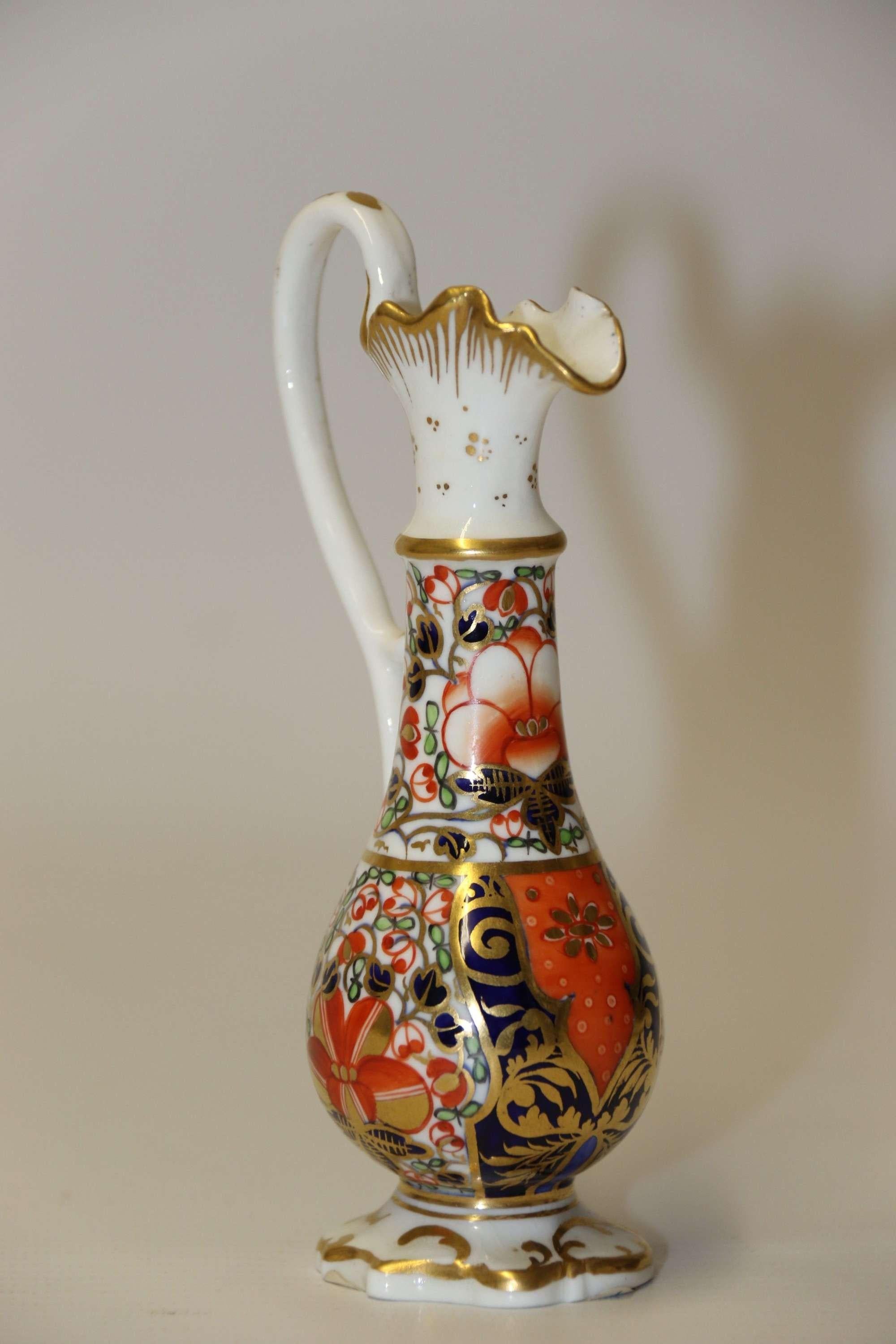 An Antique English Mid 19th Century Hand Painted Derby Ewer

This elegant mid 19th century English Derby Ewer is of a slender design with a scrolled handle and a shaped foot. The main body is beautifully hand painted with flowers and foliage in rich