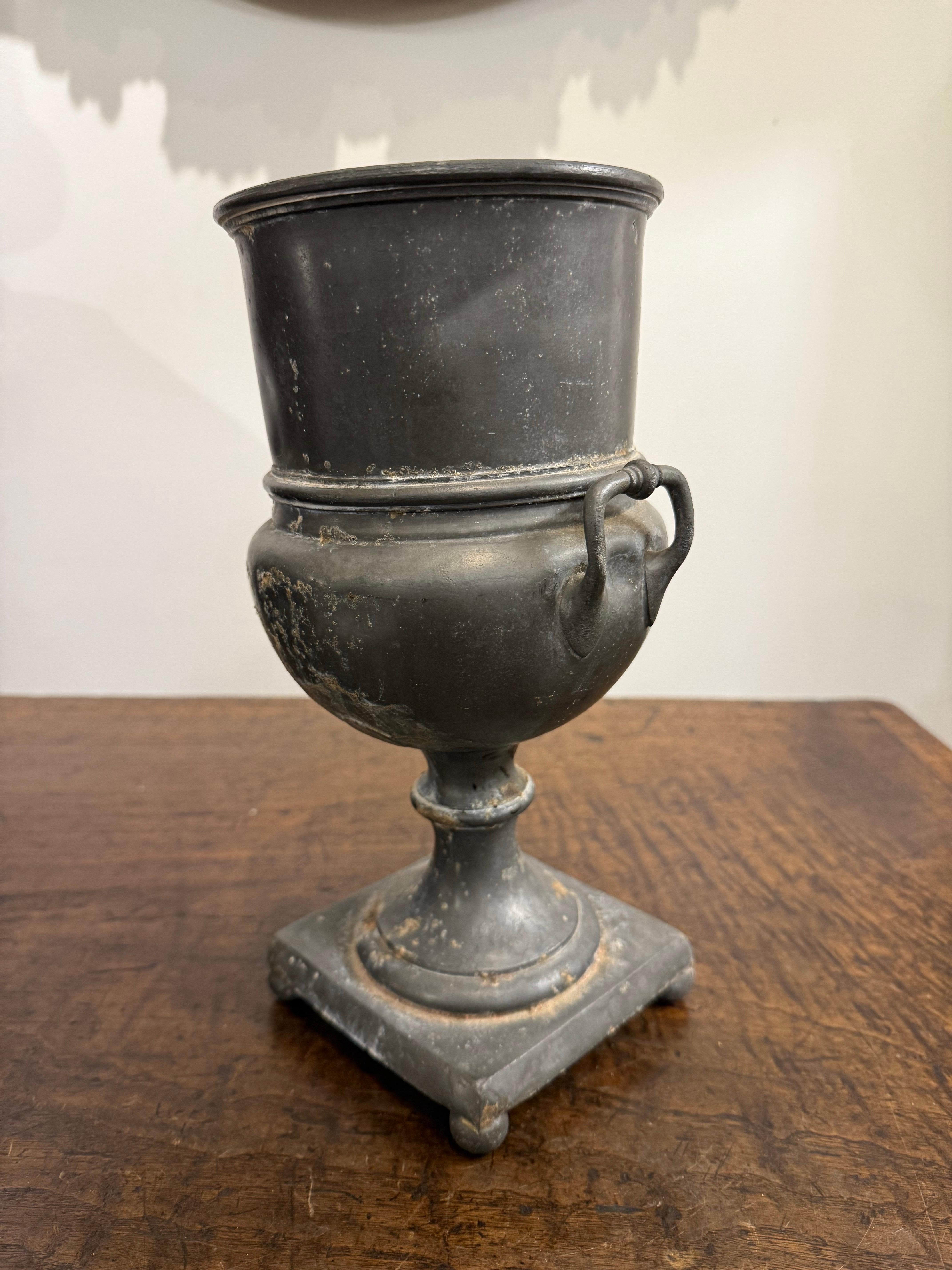 Antica urna inglese in peltro con marchio, XIX secolo
Ha una classica forma a urna con due manici e un bordo svasato.

Provenienza: Collezione privata australiana.

Dimensioni:
Altezza: 28 cm.
Larghezza: 14,5 cm.
Profondità: 13 cm.