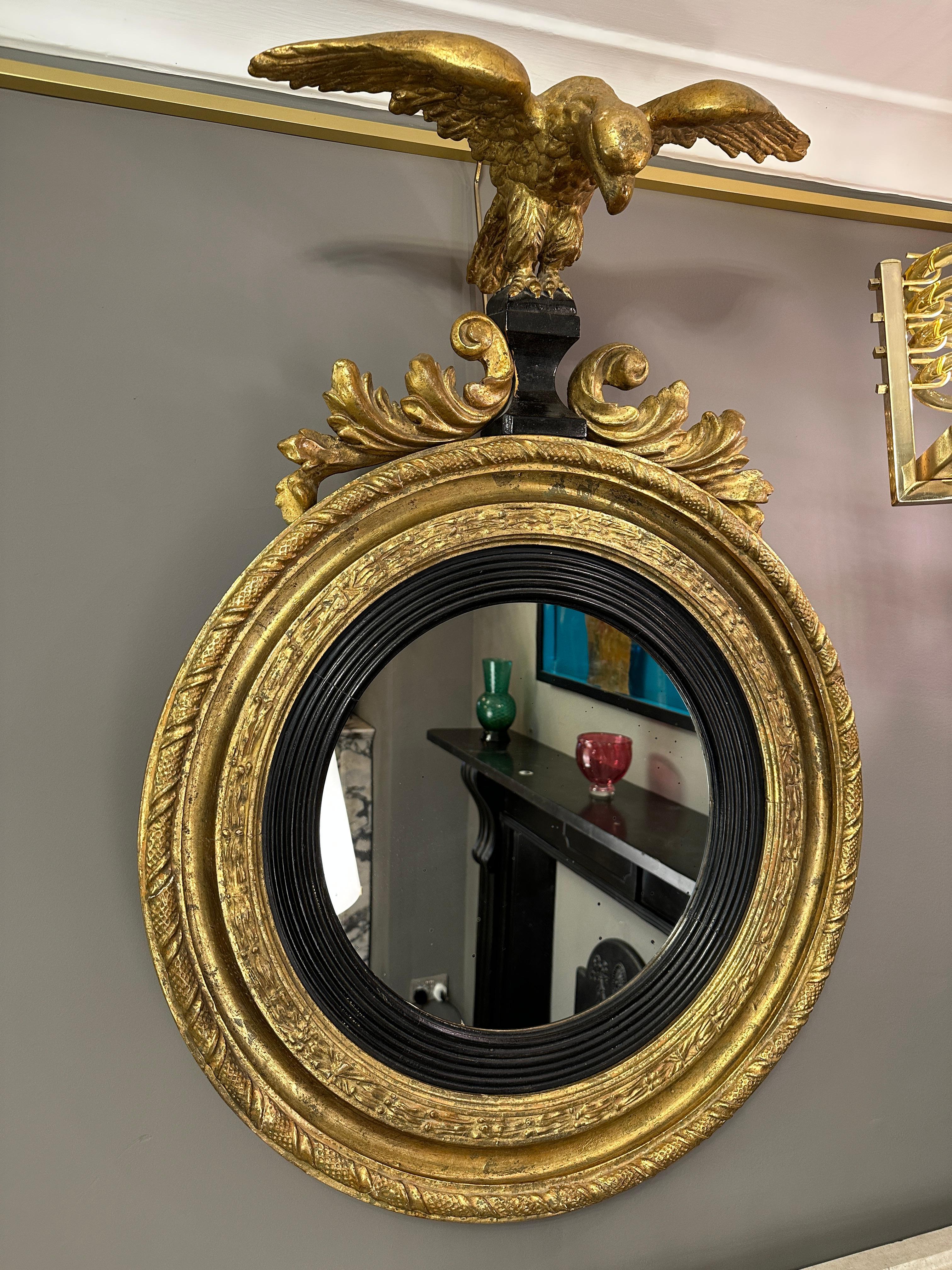 A 19th century English Regency period Giltwood mirror. Having good size and proportions, the frame with outer twist ribbon design, inner design of crossed ribbon, with a generous ebonized slip surrounding the lightly foxed flat mirror plate. The