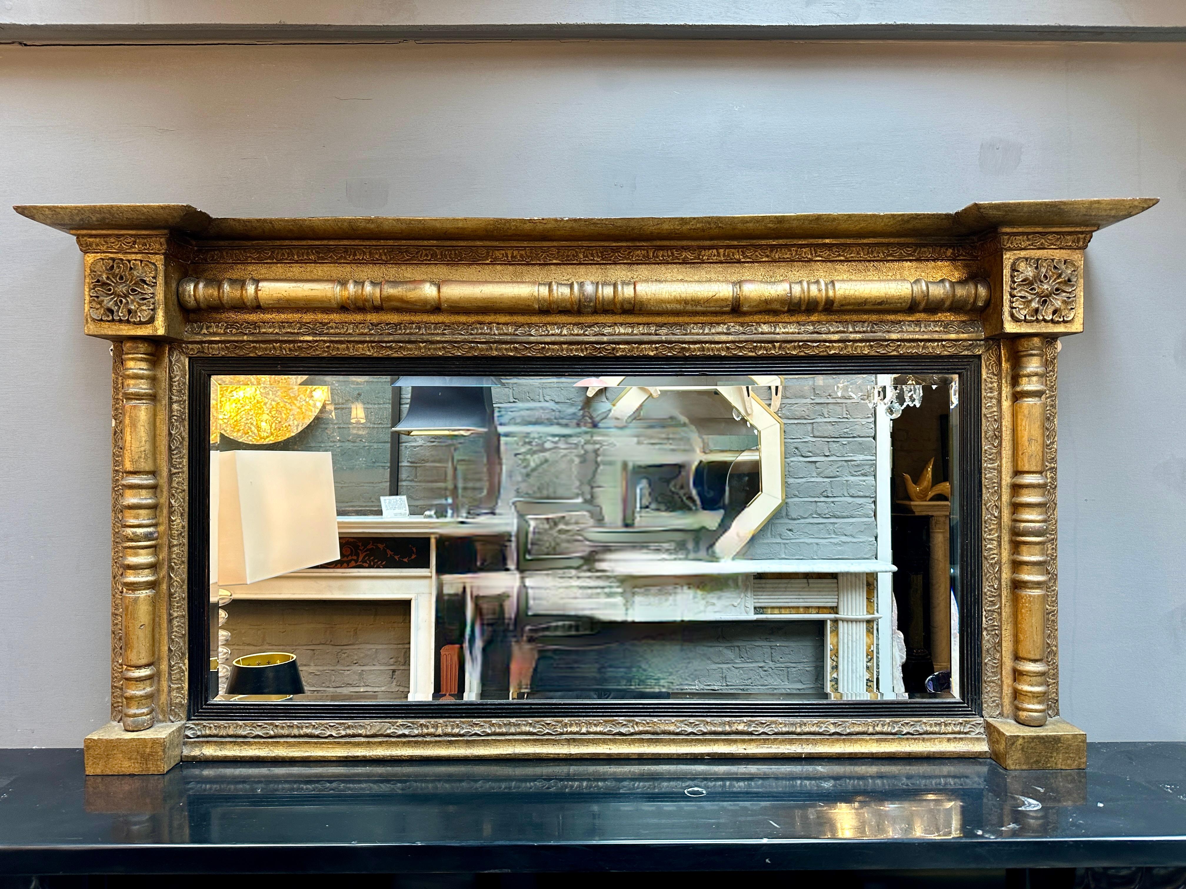 Ein Regency vergoldetes Holz Overmantle Spiegel aus dem frühen Teil des 19. Jahrhunderts, mit seinem origianl Glas abgeschrägte Platte und ebonisiert geriffelt inneren slip.
Der Rahmen mit gebrochenem Giebel, quadratischen Patarae-Ecken,