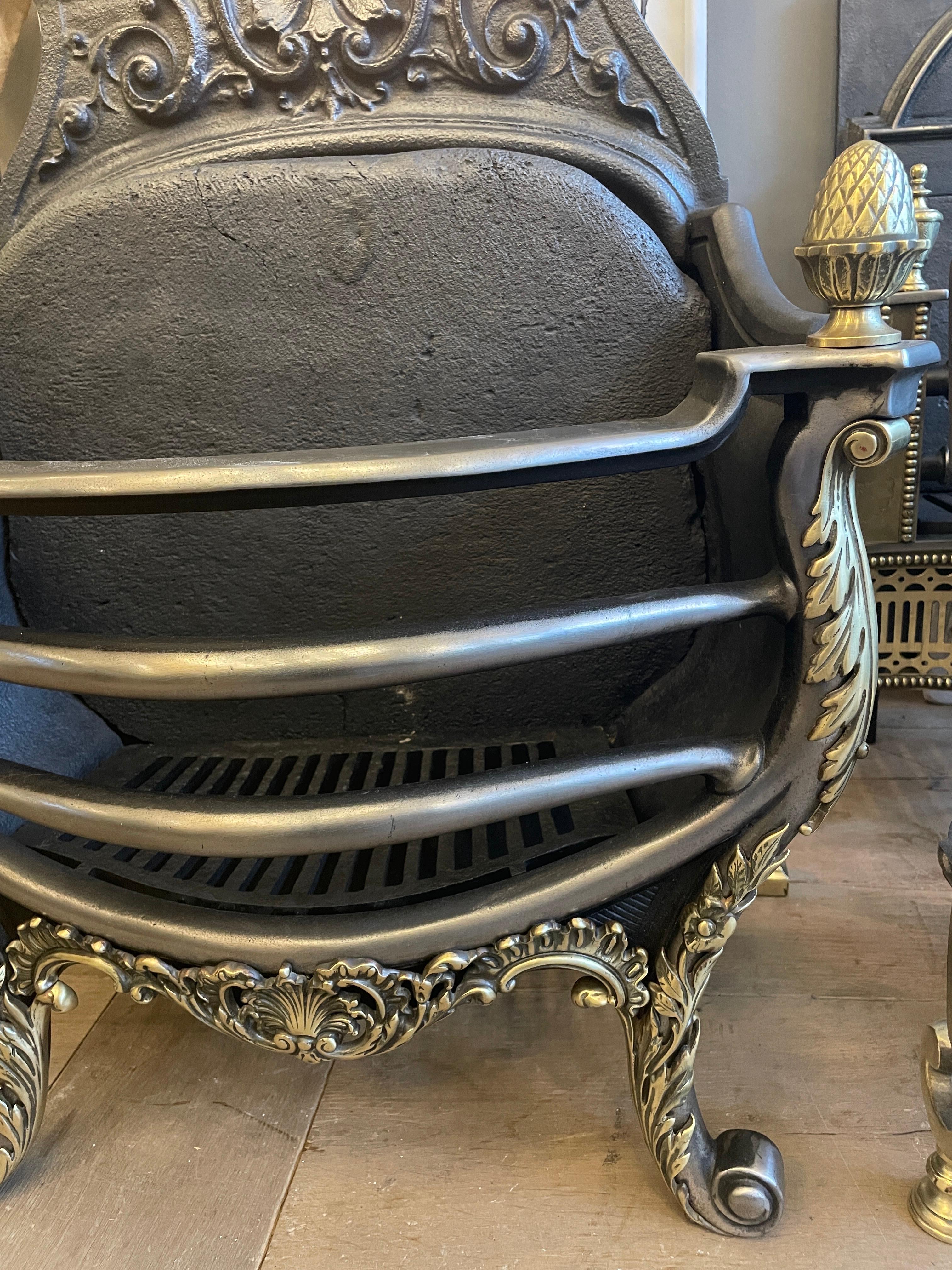 A large English late 19th century Rococo style fire basket in brass and cast iron. Dated on back plate, with a very decorative pediment in the Rococo taste, with a large shaped fire brick within. The polished bowed bars of the burning area