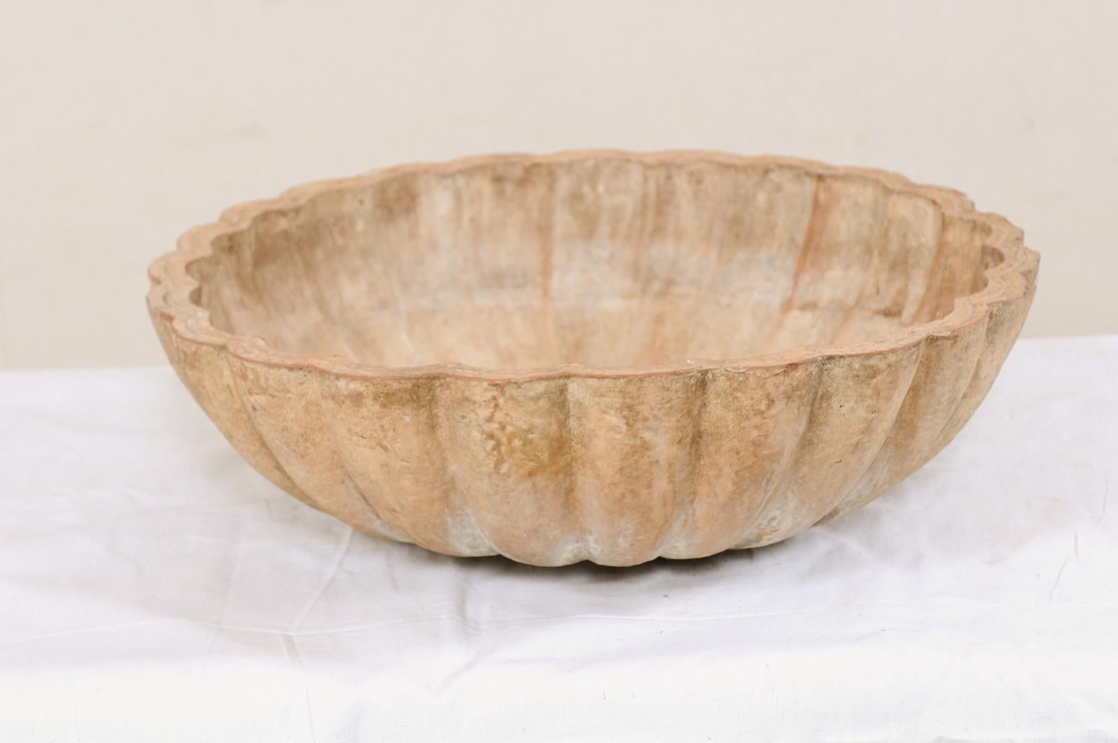 A European terracotta basin from the early 20th century. This antique fountain sink from Europe has a round-shape, with scalloped movement about the outer and inner perimeter. The coloring is subtle warm and cool tones with a nicely aged patina. A