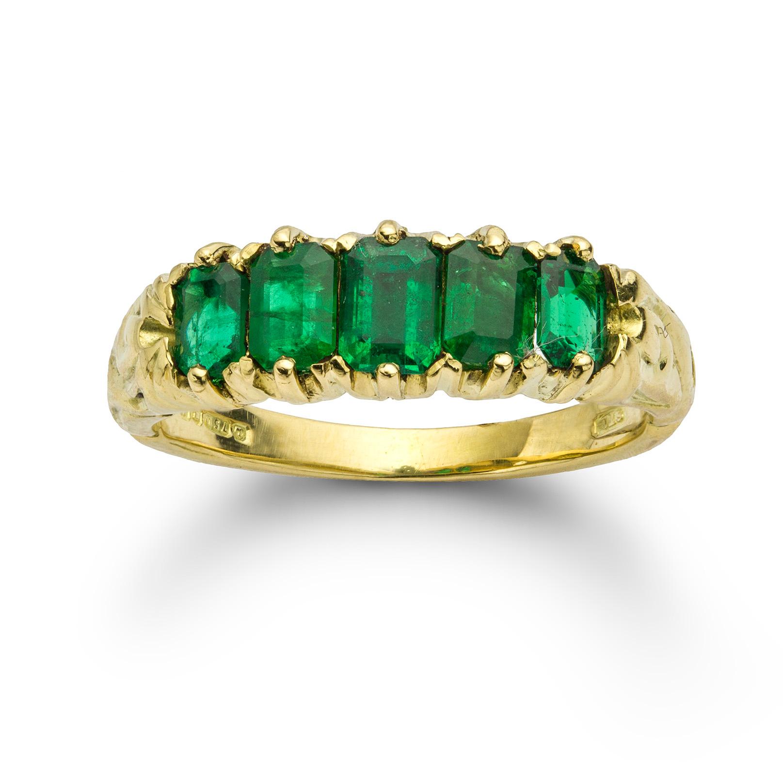 An antique five stone emerald ring, the five octagonal-cut emeralds weighing 1.1 carats in total, claw-set in yellow gold mount with carved shoulders, hallmarked 18ct gold, London, 1998, measuring 2 x 0.6cm, finger size M, gross weight 4.9