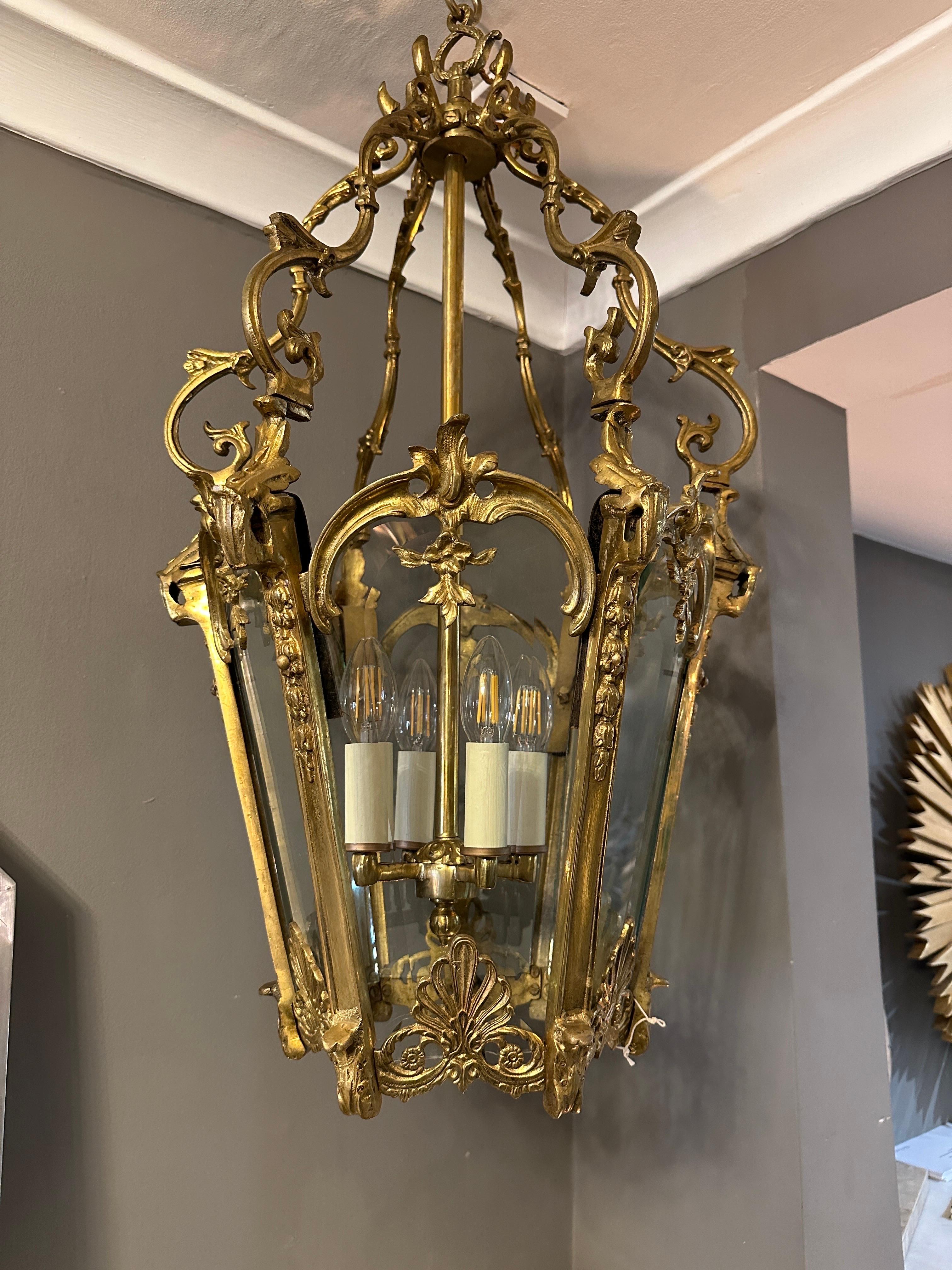 Große antike französische Rokoko-Laterne im Louis XV-Stil aus vergoldeter Bronze mit sechs geschliffenen, abgeschrägten Glasscheiben und einem kunstvollen Baldachin mit Akanthusranken und Blattwerk. Die Glastafeln sind mit einer C-Schnecke und