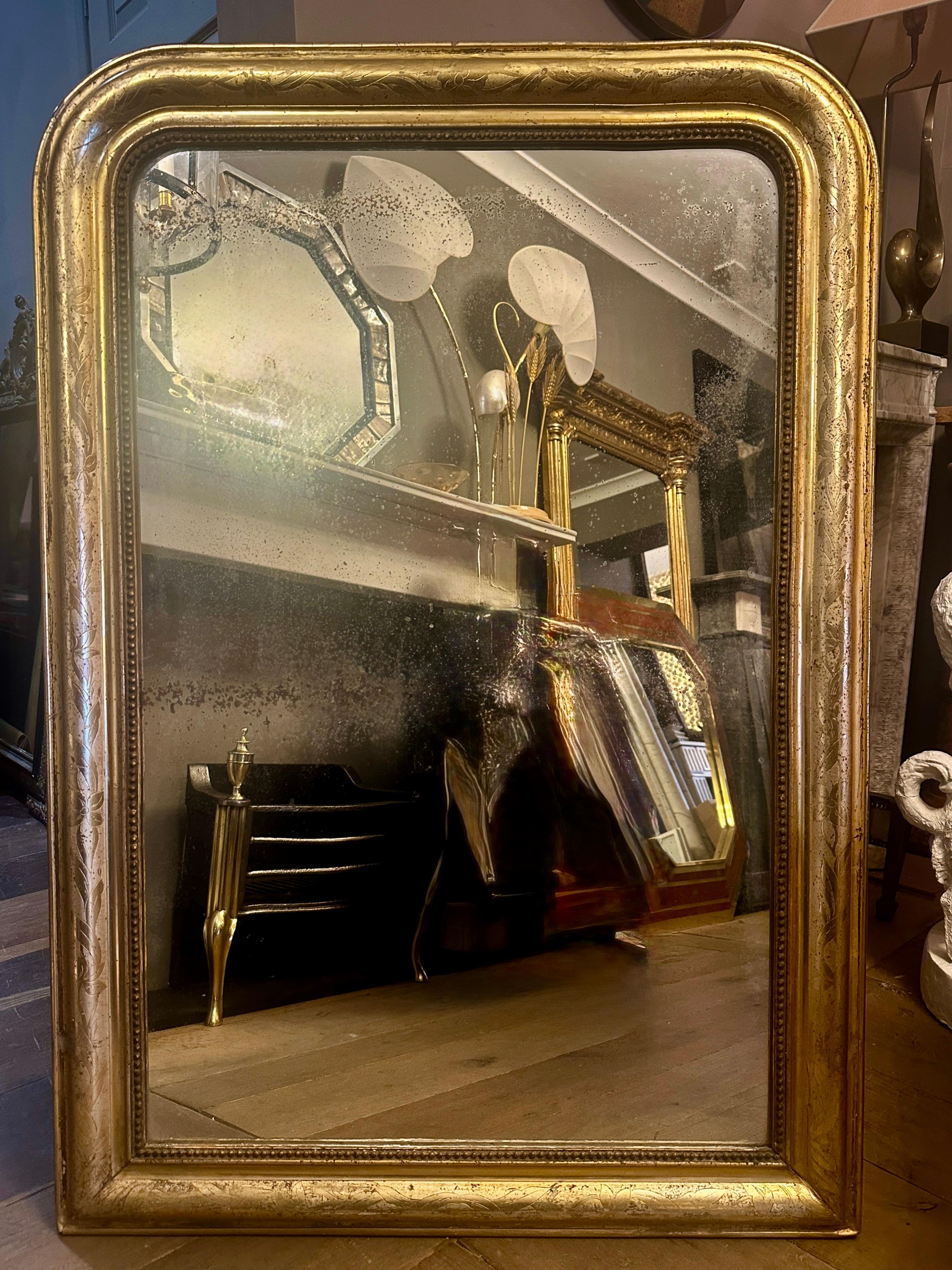Miroir doré à dôme Louis Philippe, avec une dorure florale brillante et une plaque de verre d'origine légèrement vieillie. Les images reflètent fidèlement l'état de l'objet et montrent les rousseurs et l'état du verre. Dos cartonné d'origine. Patine