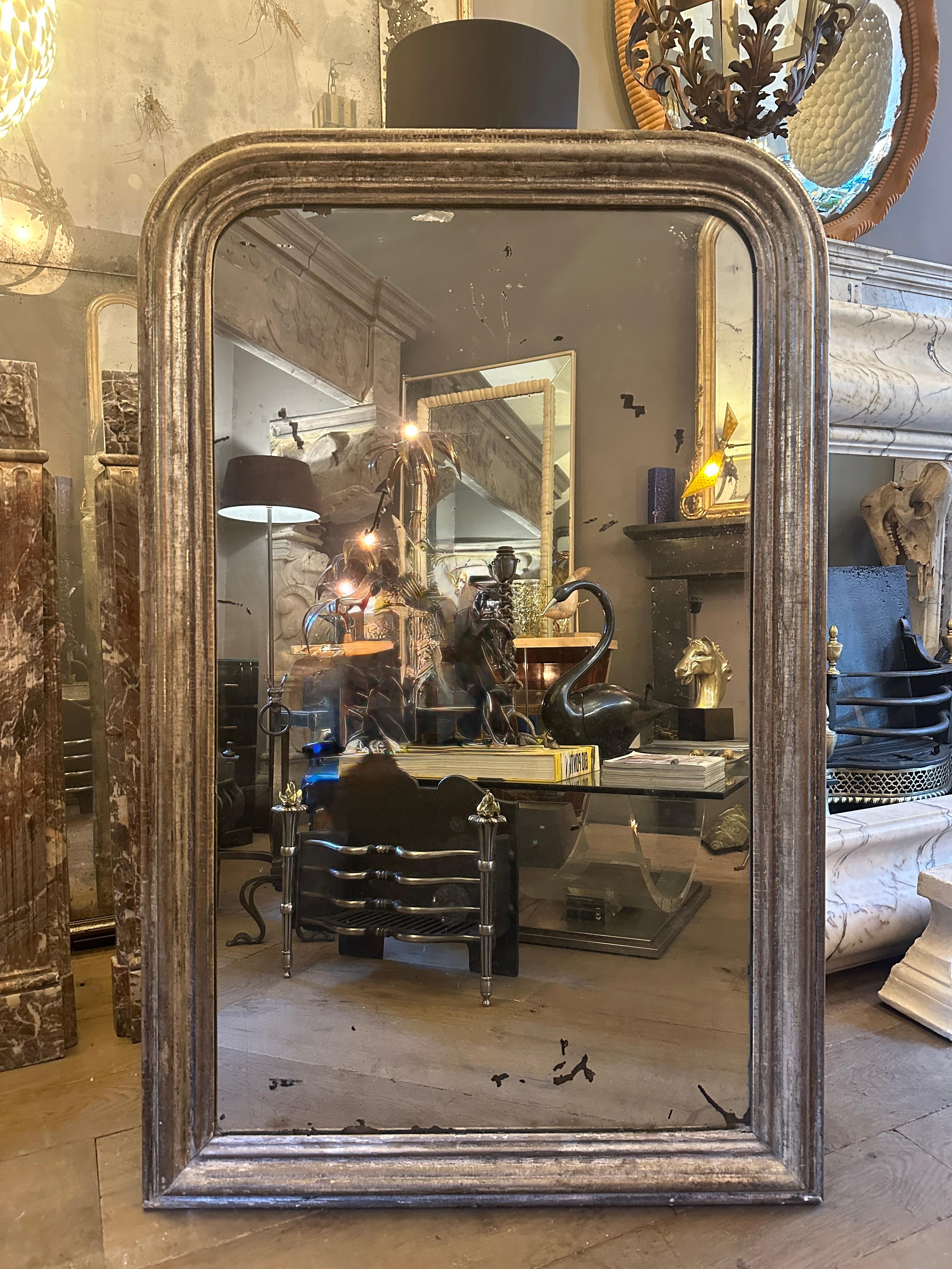 A wonderfully distressed silver gilt domed topped Louis Philippe mirror, with distressed and foxed silver mirrored plate. The frame with worn and soft patina, retaining the silver gilt. The original plate with areas of loss and foxing. 
Boarded back