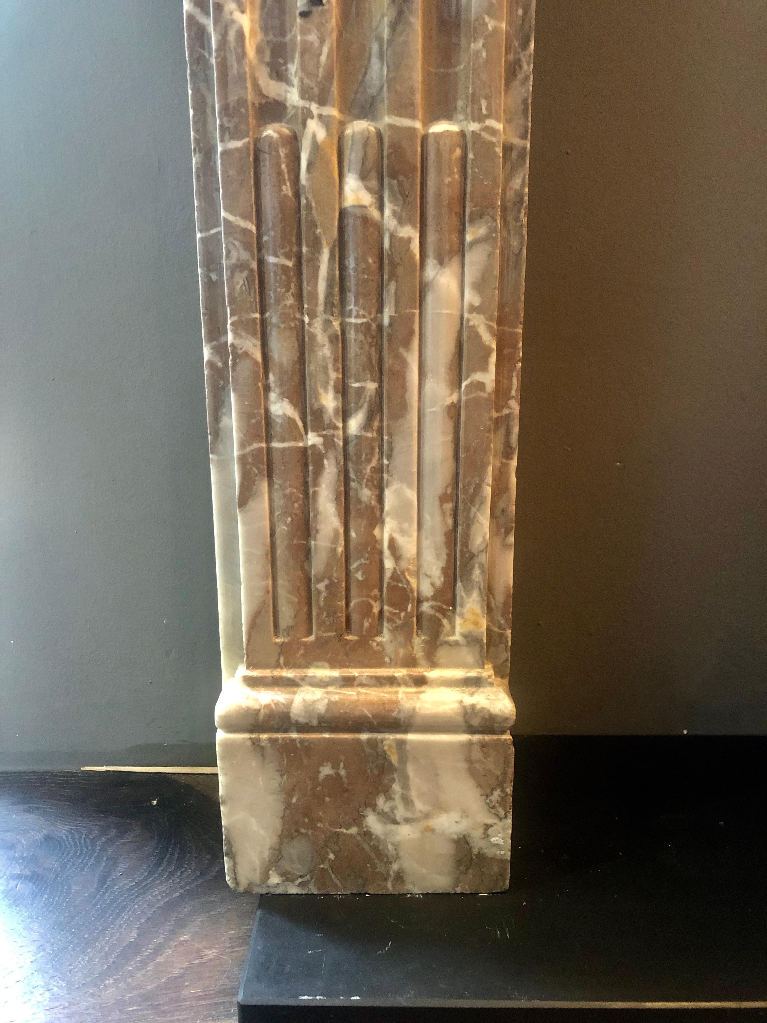A 19th century Louis XVI style mantel in Rogue Royal marble. The plain fielded frieze with carved patarae end blocks, beneath a simple edged mantel. The jambs on square foot blocks and stop fluted panels.

Opening size 
114cm W x 87cm H.