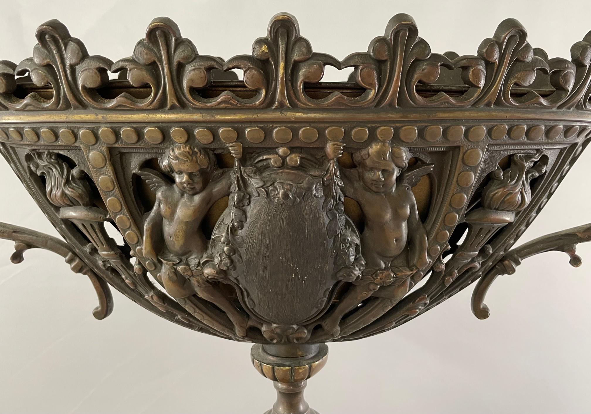 A 19th century antique French patinated bronze tri-pod vase or urn featuring cherubs, foliage and torches. The vase rim or mouth is finely crafted in acanthus motif. Timeless and classy, the vase or urn is a statement piece that will elevate any