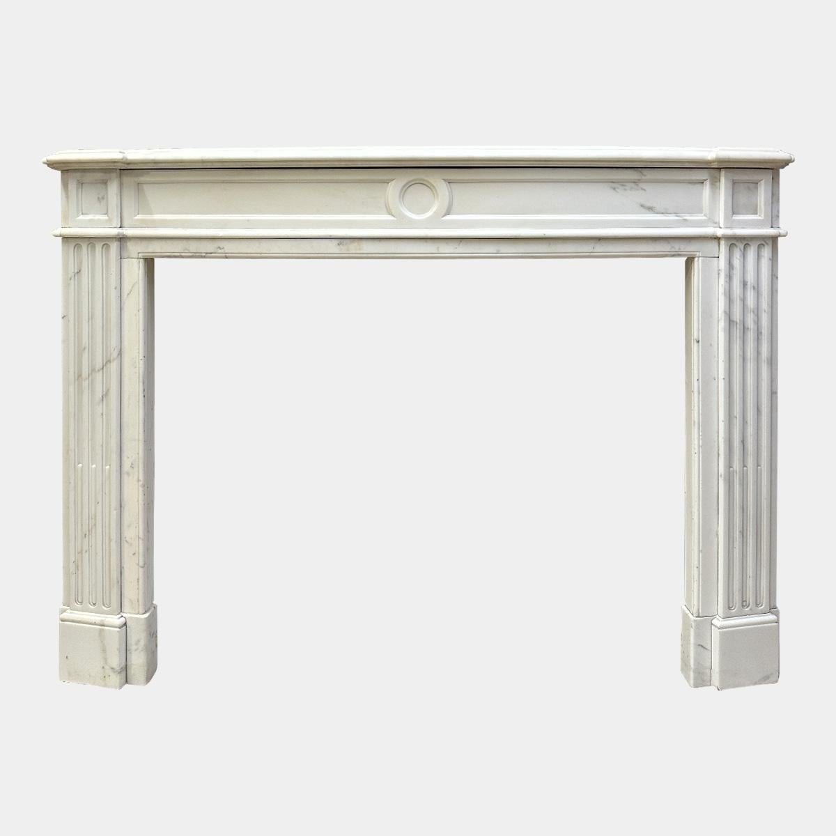 An antique 19th century Statuary white marble Louis XVI style fireplace mantel, with bow fronted frieze and shelf. The jambs with deep side returns and fluted front panels terminating in square fielded corner blocks. the bow fronted frieze again
