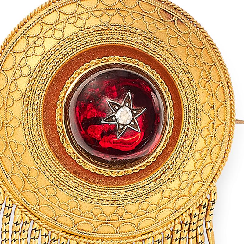 An antique garnet and diamond mourning tassel brooch, in the Etruscan revival manner, the circular body set at the centre with a garnet cabochon accented by a rose cut diamond within star motif, encircled by beaded and twisted wirework designs,