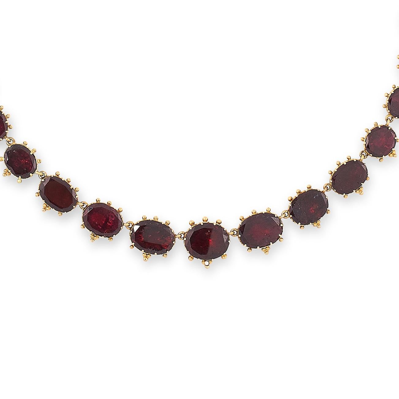 This is a glorious and regal antique garnet rivière necklace mounted in 18 karat yellow gold, comprising a single row of thirty-one graduated flat oval cut garnets, accented by beaded borders, French assay marks.