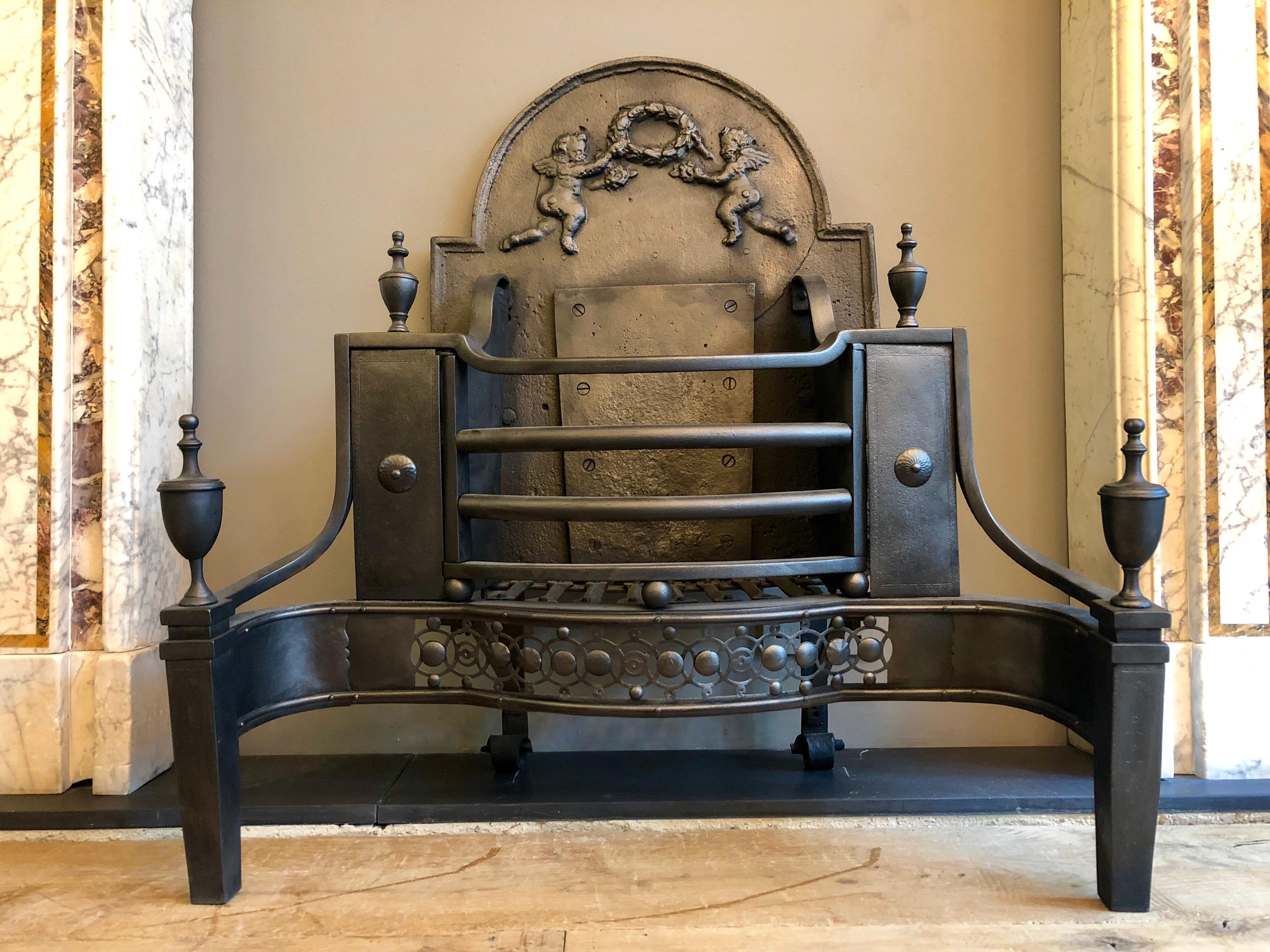 An unusual English 19th  century large fire grate. The pierced guilloche fret with cut steel buttons, surmounted by shaped front bars. The curved wrought iron wings flanking engraved front panels with rosette to centre. Engraved front legs with