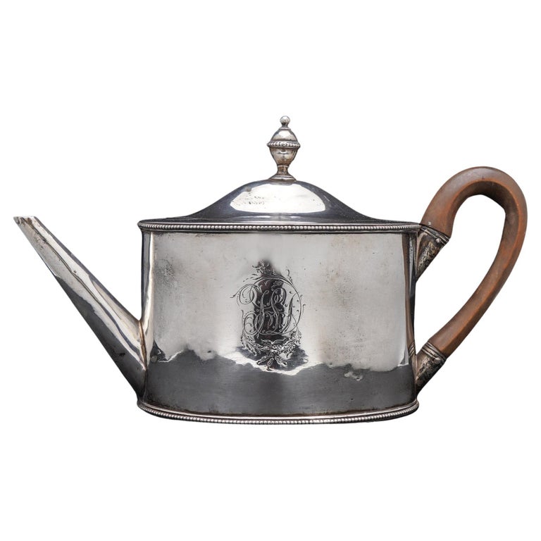 An Antique George III sterling silver oval tea pot.
This tea pot is oval in shape with straight sides, has a wooden handle. 
The body engraved with monogram. 

Made in England, London, 1784
Maker: Benjamin Mountigue
Fully