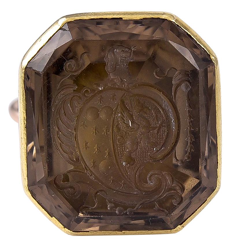 The support of Gothic Revival form to a shell motif frame base.
The attractive Smokey Quartz (sometimes called Smokey Topaz)
is deeply engraved with a swirling Crest containing a winged Griffon and several darts and circles and at the top of the