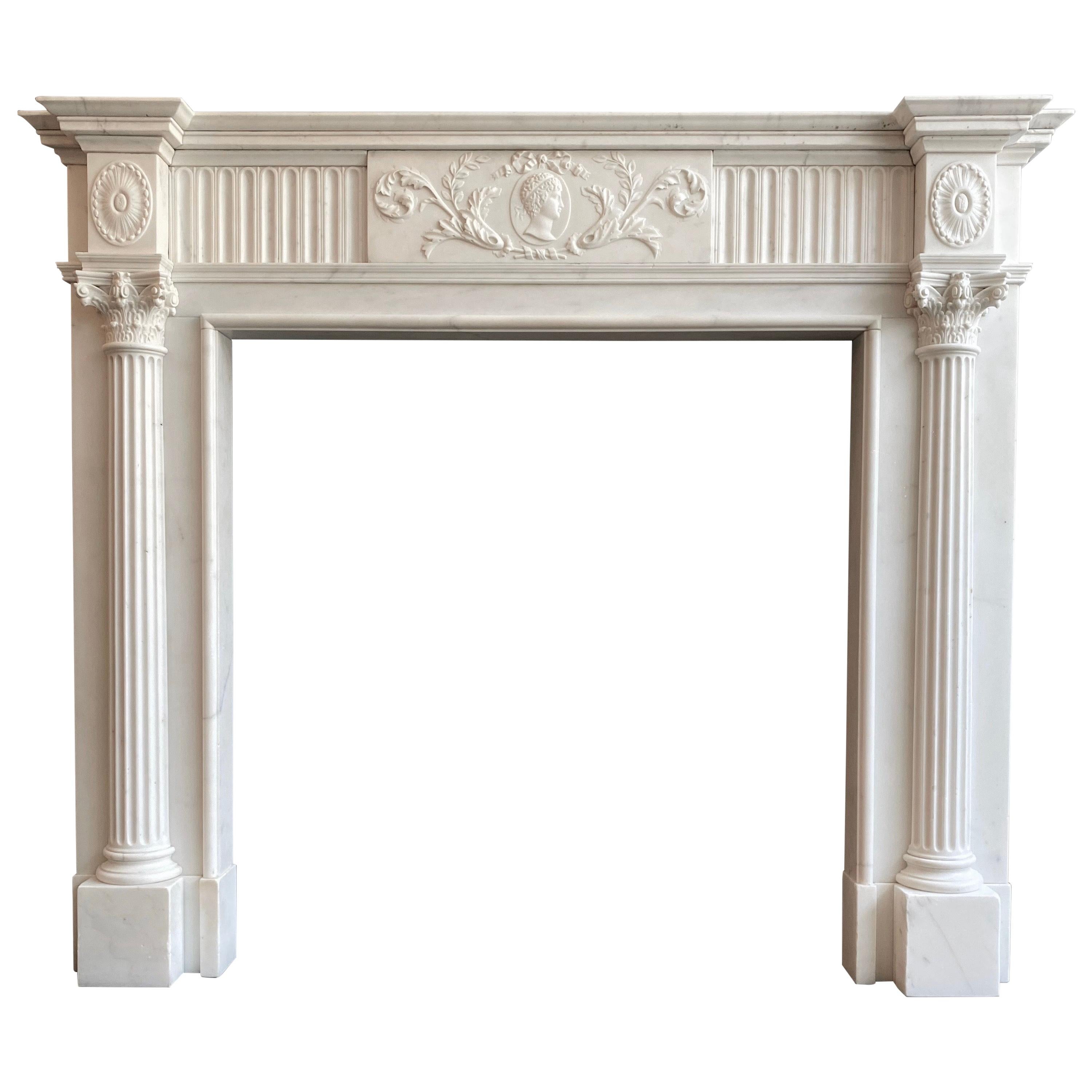 A late 18th century exquisitely carved George III chimneypiece executed in Statuary white marble. The central tablet carved with a male Greek medallion, with bow tied ribbon and scrolled acanthus. Flanked by panels of stop flutes with end blocks of