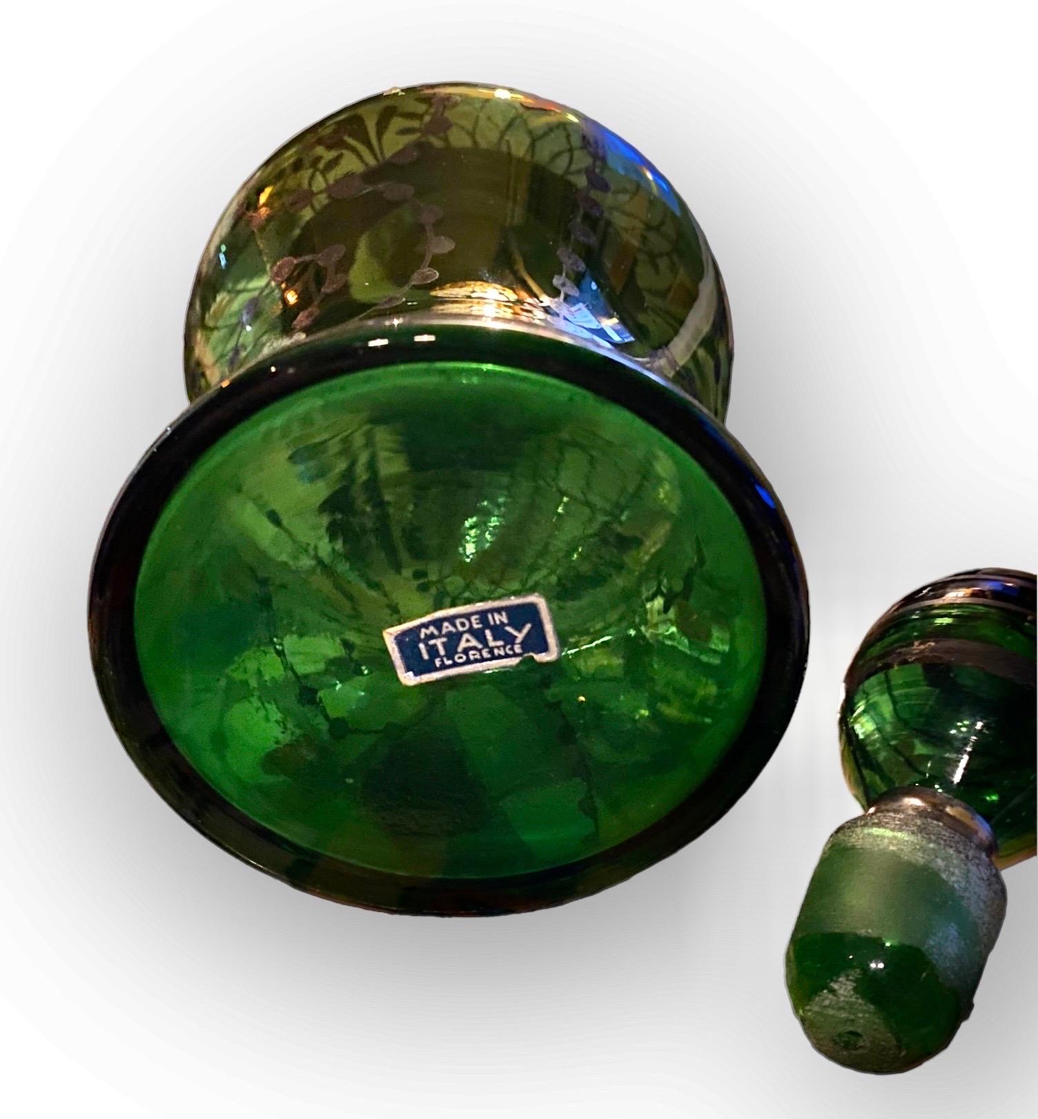 Charmante carafe en verre soufflé à la main et en argent datant des années 1920, accompagnée de quatre verres dans de jolies nuances de vert émeraude, avec des motifs en argent et des rebords en argent. Le bouchon de terre avec des bandes d'argent. 