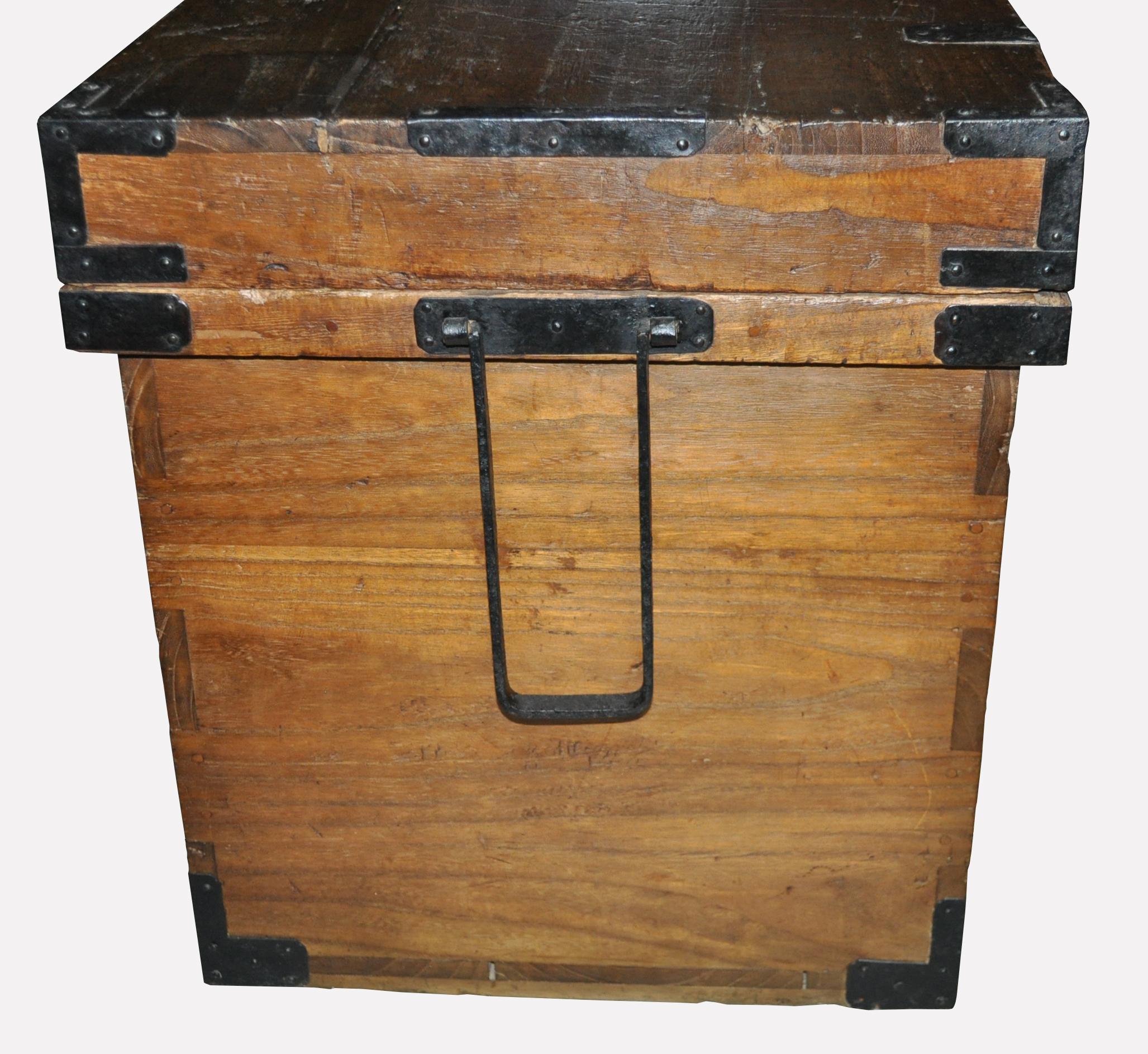 A most auspicious antique Japanese money chest of old kiri wood with mitered mortise and tenon construction and hand wrought iron fittings, including the original sao-toshi (suspending handles). Bold calligraphic characters on the back of the chest
