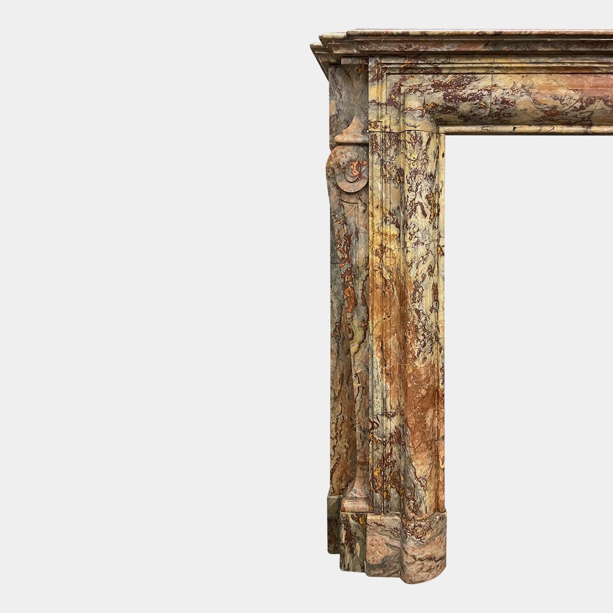 A late 18th century Louis XIV style fireplace in rich and highly variegated Sarrancolin Fantastico marble. The stepped shelf breaking back to follow the returns on the jambs, which have outward left and right facing swept scrolled brackets with