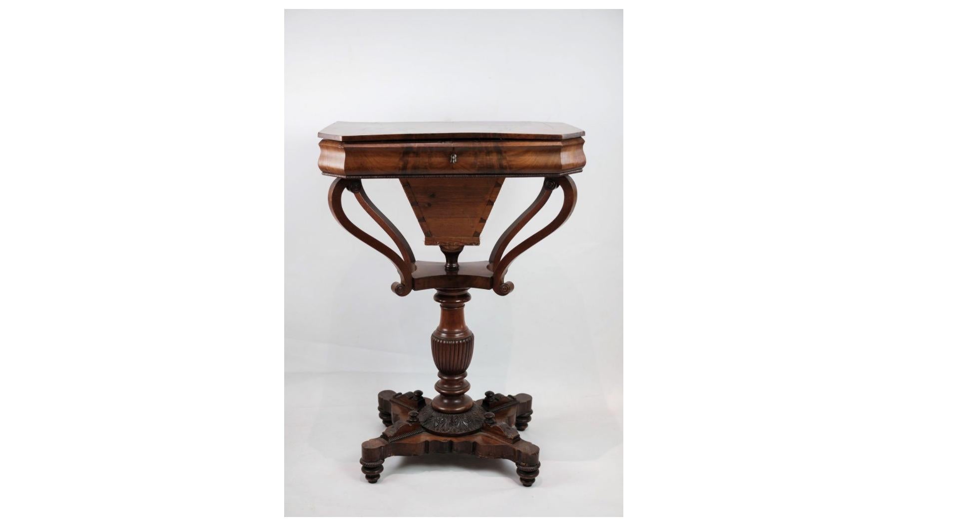 The antique mahogany sewing table on a pillar from around the 1840s is a captivating piece of furniture that exudes charm and history. Crafted from rich mahogany wood, known for its durability and luxurious appearance, this sewing table showcases