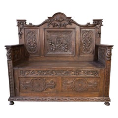 Un banc médiéval ancien, sculpté, avec espace de rangement