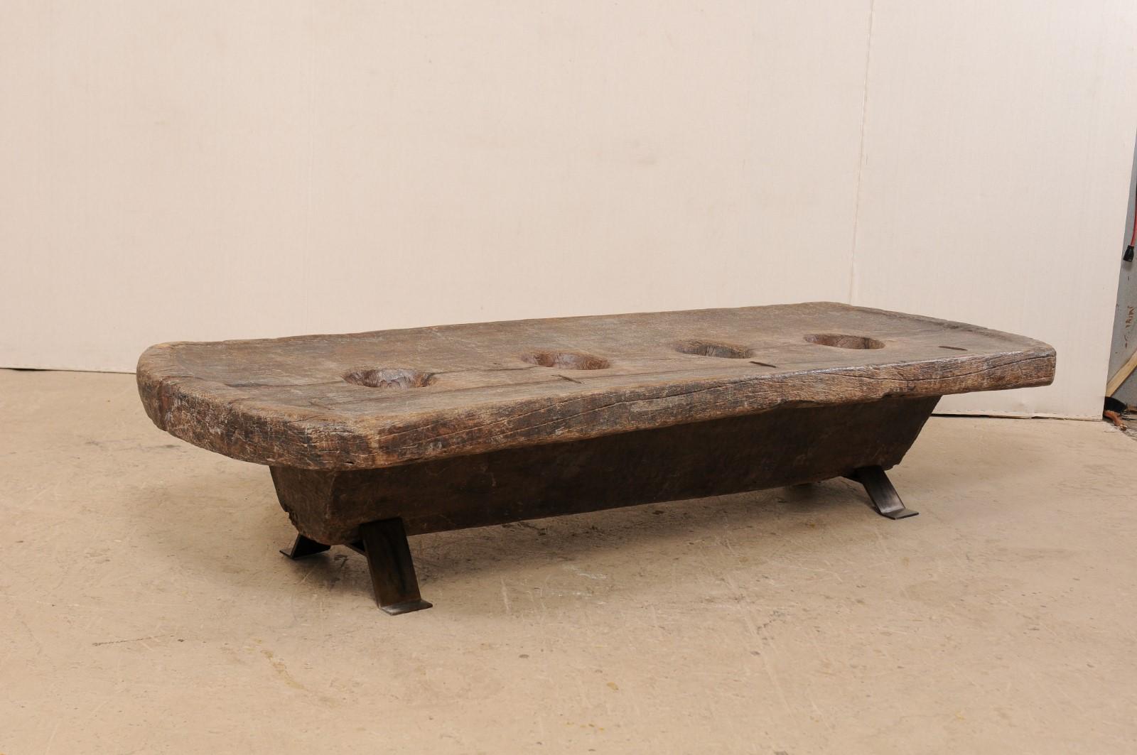 A Naga table from the late 19th to early 20th century. This hand-carved table from Nagaland, India was originally use by the Naga tribes of North East India as a grinding table, for grains such as millet. The three holes within the center are where