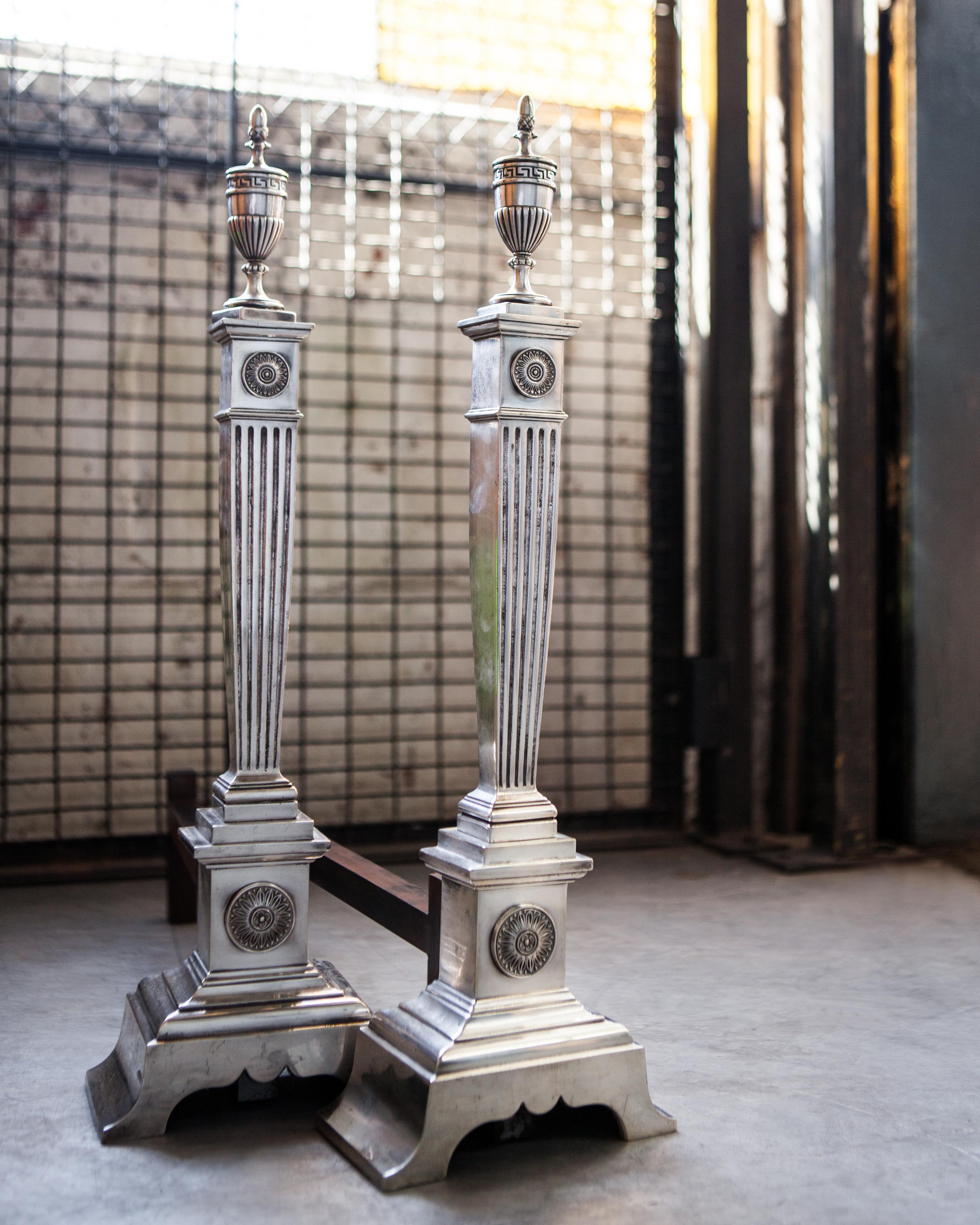 20ième siècle Chenets néoclassiques en métal argenté avec colonnes cannelées et fleurons en forme d'urne, vers les années 1910 en vente