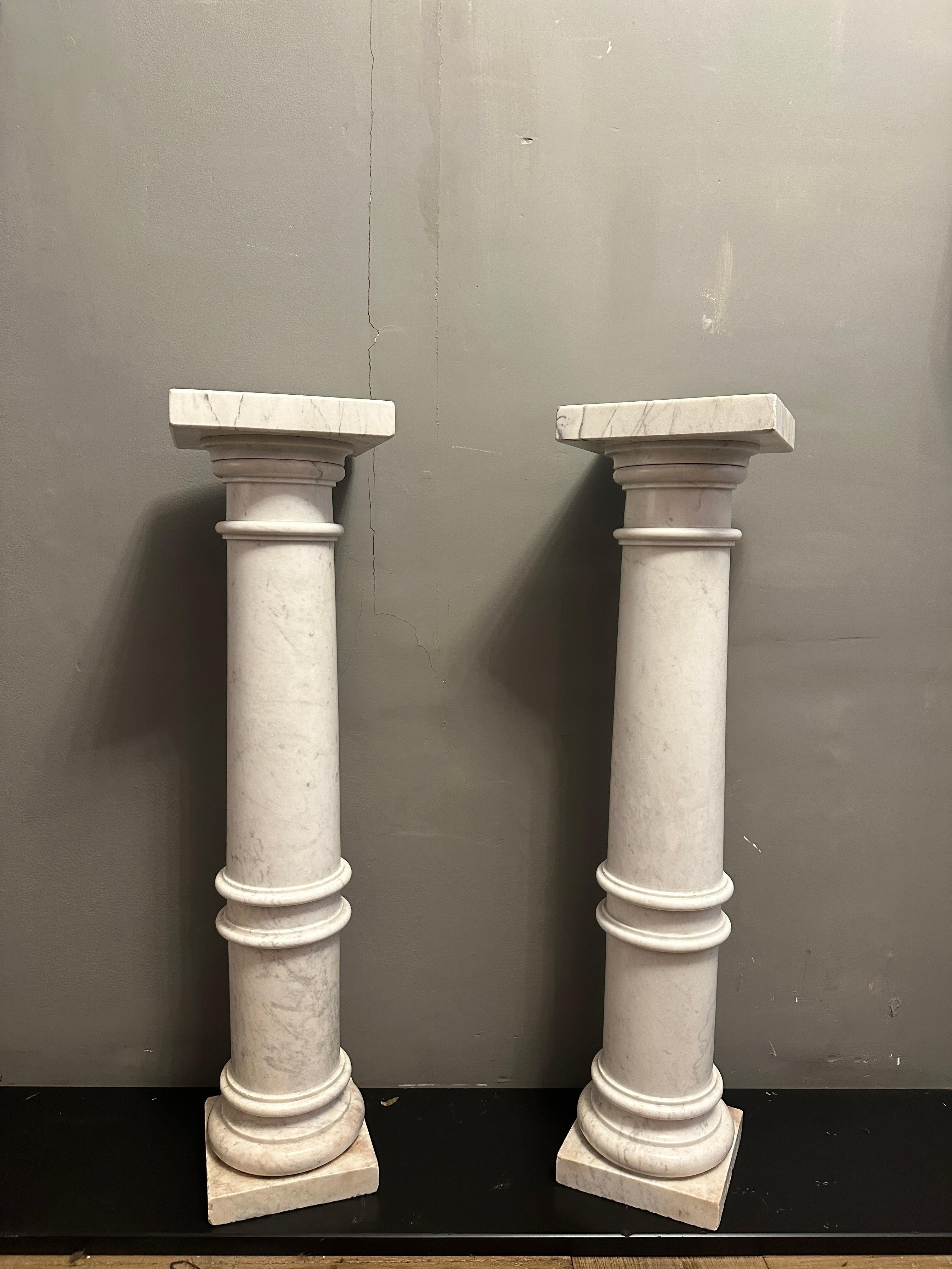 Ein kontinentales Paar antiker Sockel aus weißem Carrara-Marmor. Quadratische Basis und Sockel mit leicht bauchigen, konischen Säulen, die in quadratischen Kapitellen enden. Guter Zustand für das Alter, gute Skala und Form. Sehr vielseitiges Paar