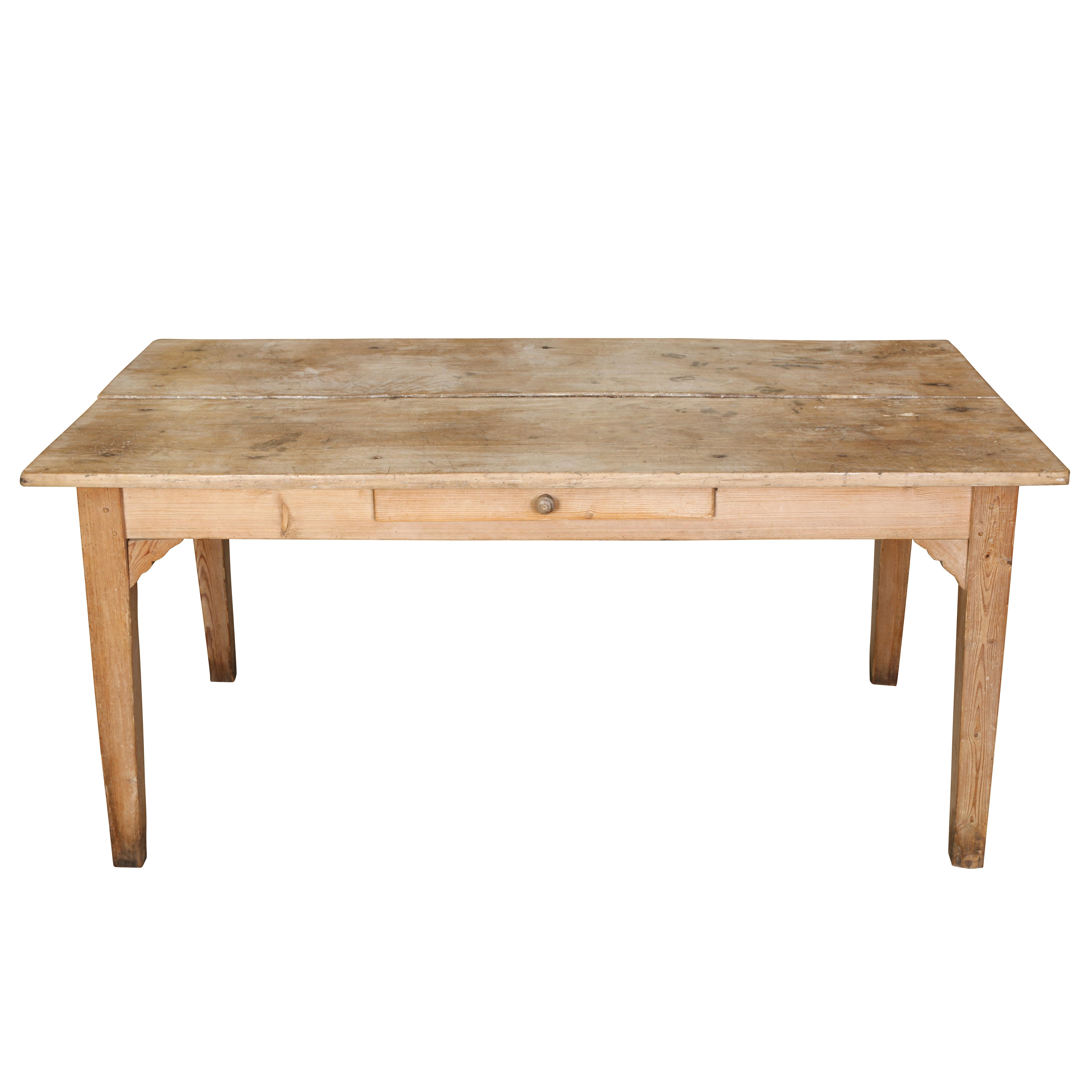 A simple yet beautiful pine dining table or work table that has acquired a lovely, warm patina over the years. The table its constructed in a straightforward way with block legs supported by decorative brackets. Its top is made of two planks of