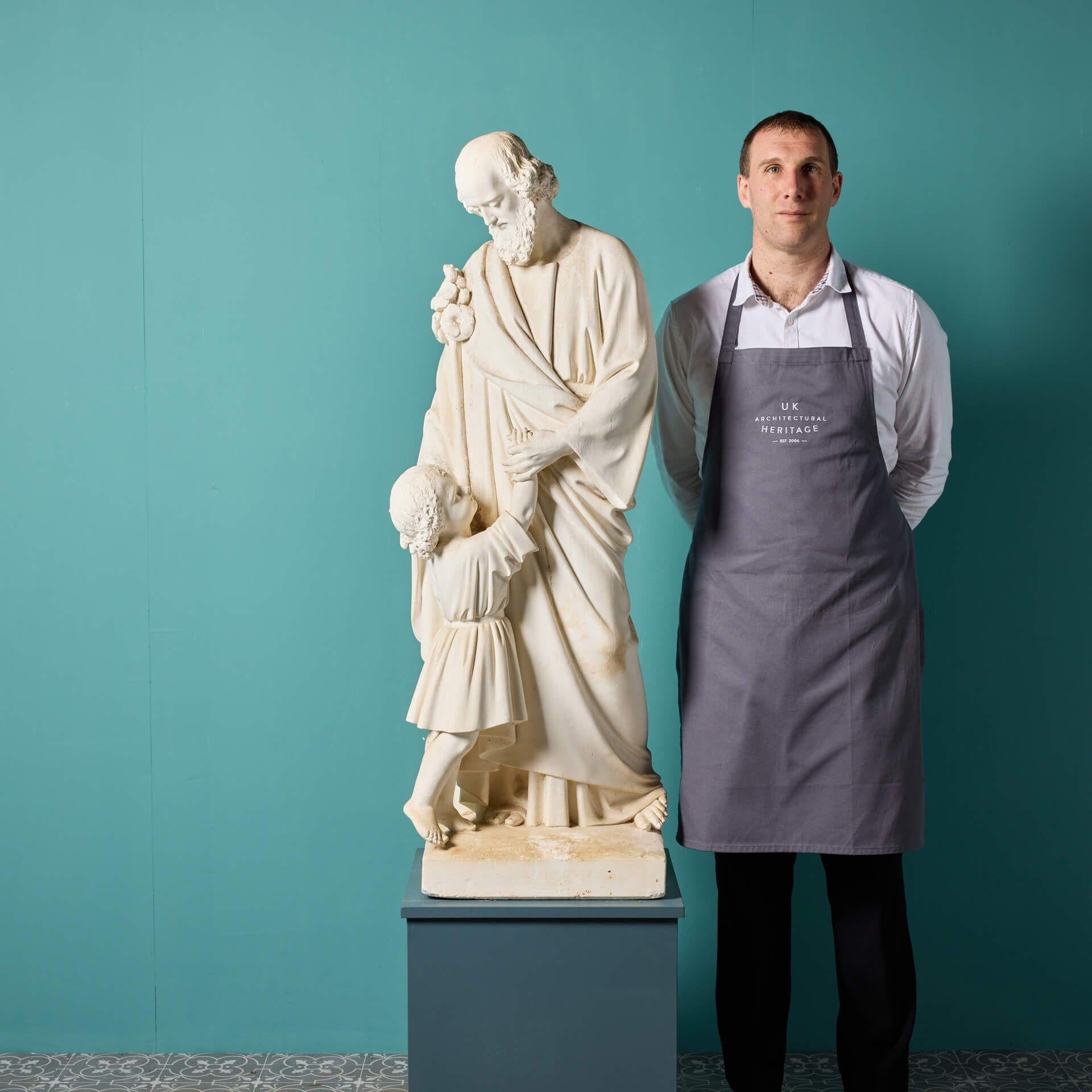 Salvaged from a church in Norfolk, this large antique plaster statue depicts St. Joseph holding the hand of a child believed to be a young Jesus. Dating from the late 1800s, this ecclesiastical statue is in good condition with only small losses and