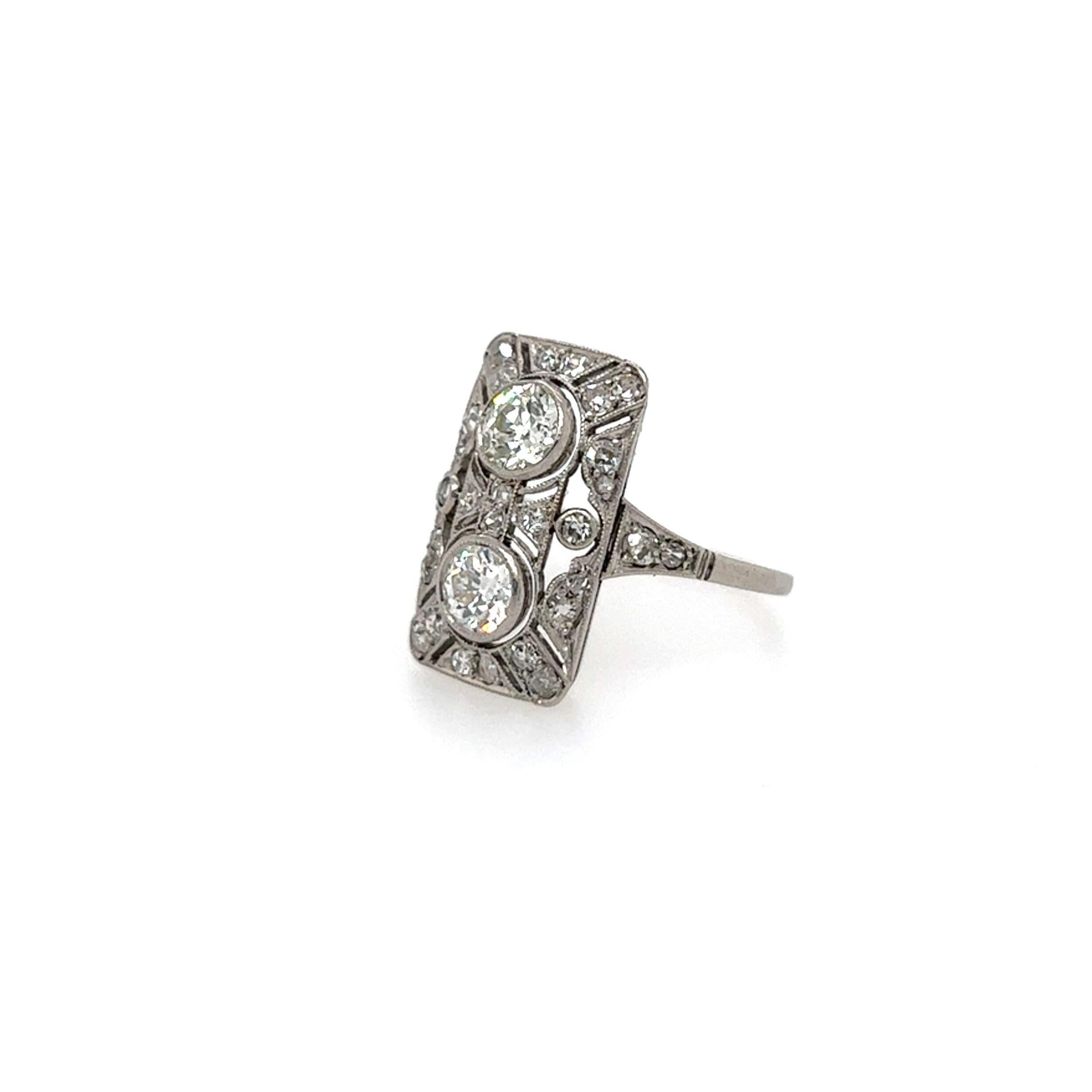 An antique platinum and diamond ring, circa 1900.  Designed as a rectangular filigree plaque centering two (2) vertically set brilliant cut diamonds of approximately 0.33 carat each, and further enhanced by an additional twenty (20) brilliant cut