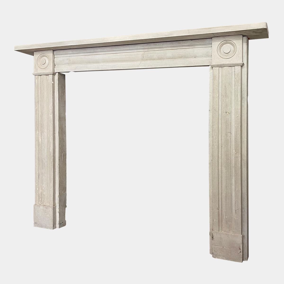 An early 19th century English Portland stone fireplace, The cushion moulded Jambs surmounted by carved roundel corner blocks and conforming frieze, all beneath a simple shelf, circa 1810 in good order and well proportioned. 

Opening Sizes 
94cm