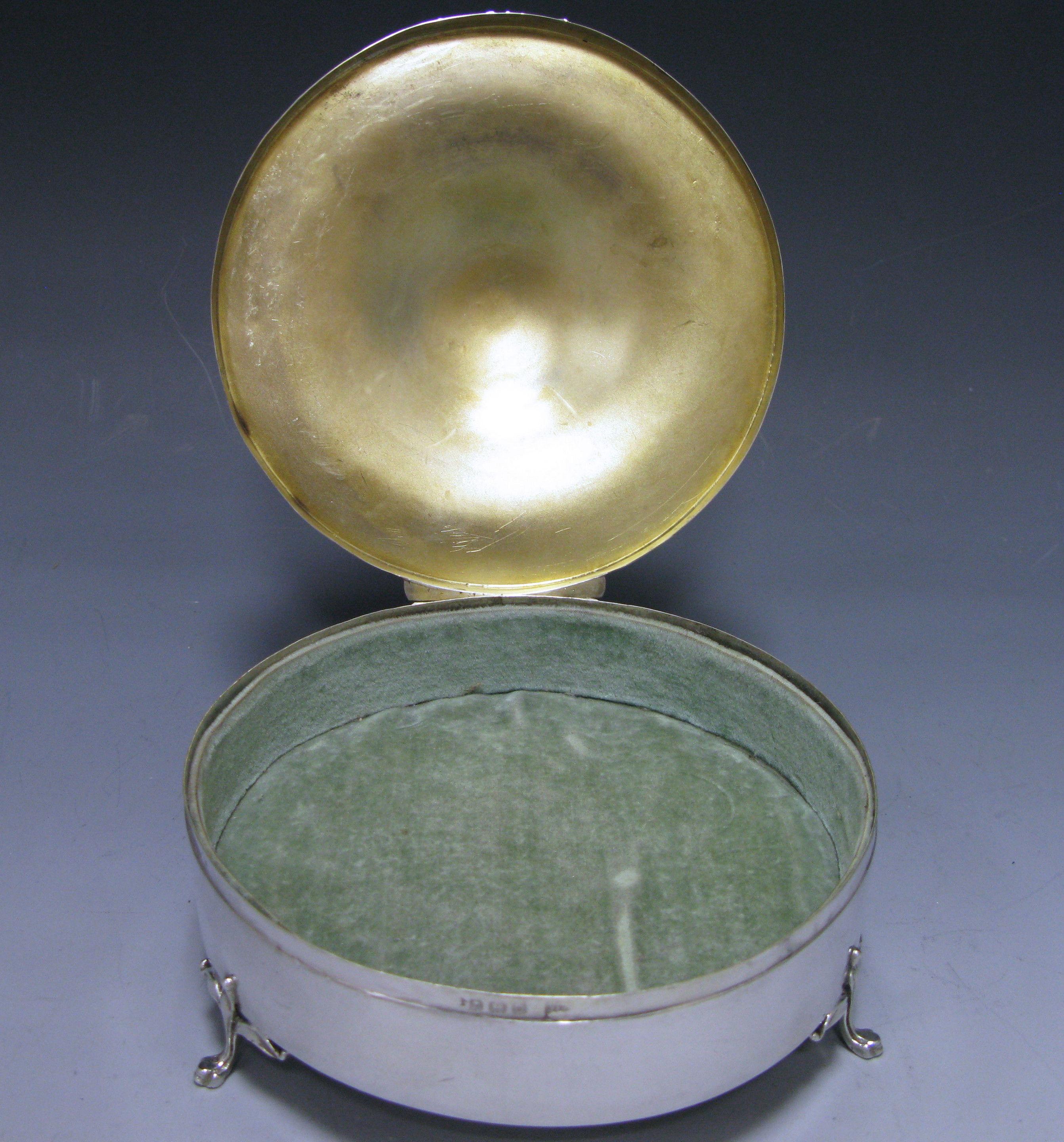 A George IV antique silver round jewel box with a domed engined turned hinged lid and a plain cartouche in the centre. The box stands on three paw moulded feet. The interior has the original pale green lining and the inside the lid is silver gilt.