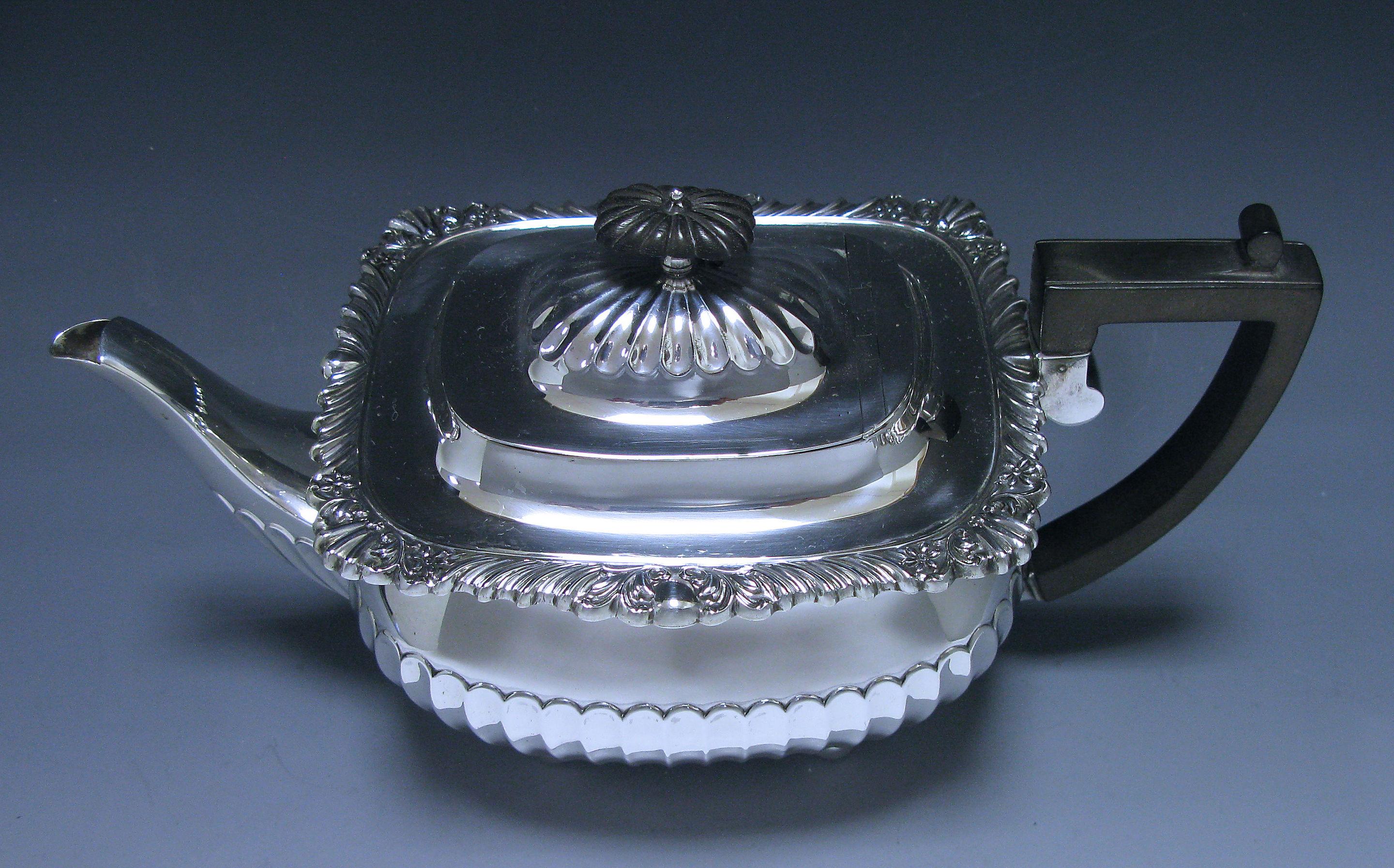 A charming antique sterling silver teapot made in the reign of Edward VII. The teapot is of rectangular form, with half fluting to the base which is repeated on the lid. The pot has a border of shell and scroll design to the top. The pot has a fruit