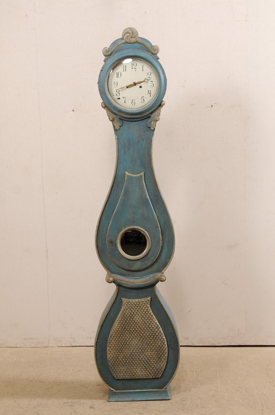 A Swedish Fryksdahl painted and carved wood floor clock from the late 18th to early 19th century. This antique Fryksdahl clock from Sweden is full of decorative accents throughout which enhance and accentuate this shapely clock. The crest or crown