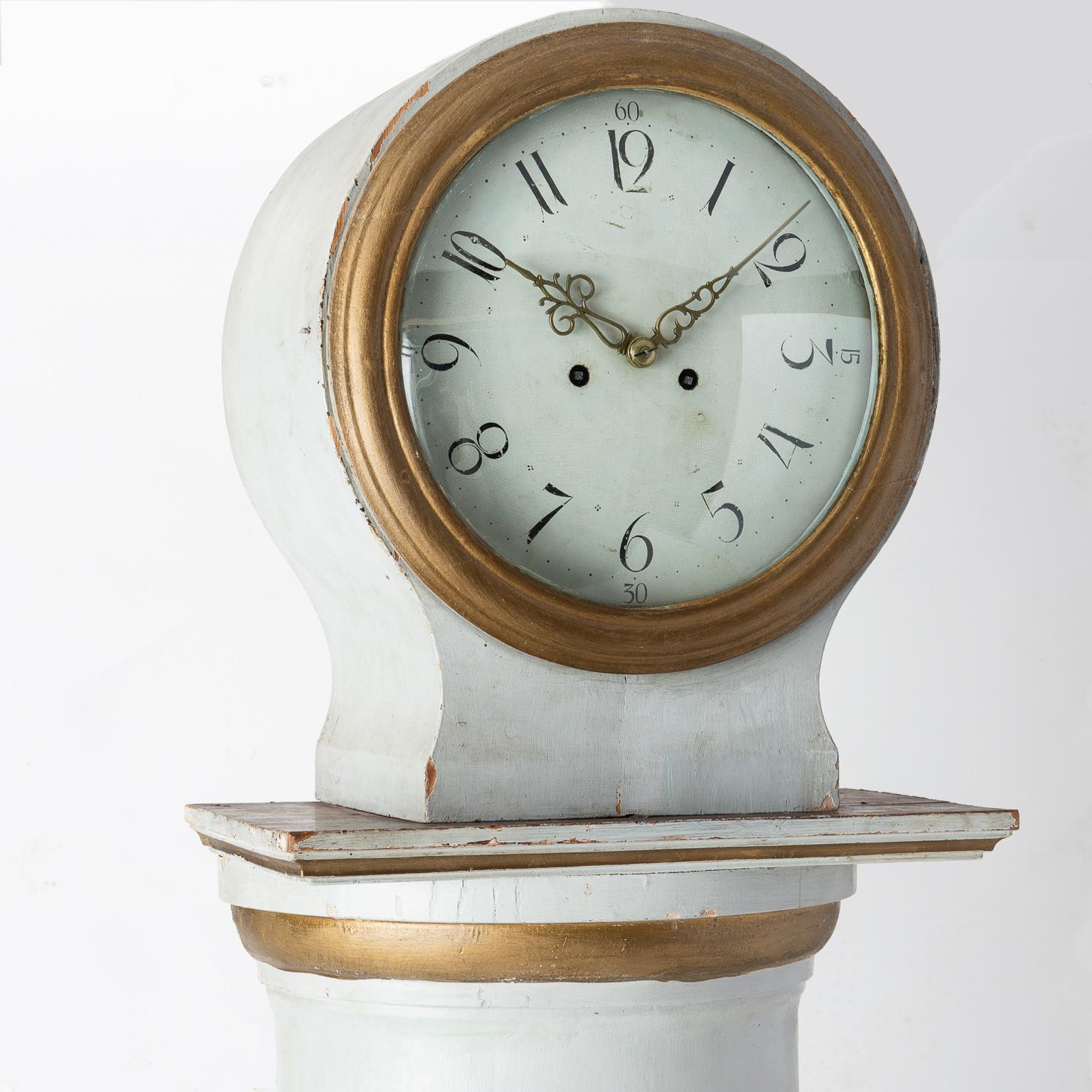 This unusual Swedish tall case clock, with inspiration from the antique Empire Period, imitates a Doric style fluted column, composed of a half-cylindrical body placed on a square base. This type of clock was often painted white with gilt