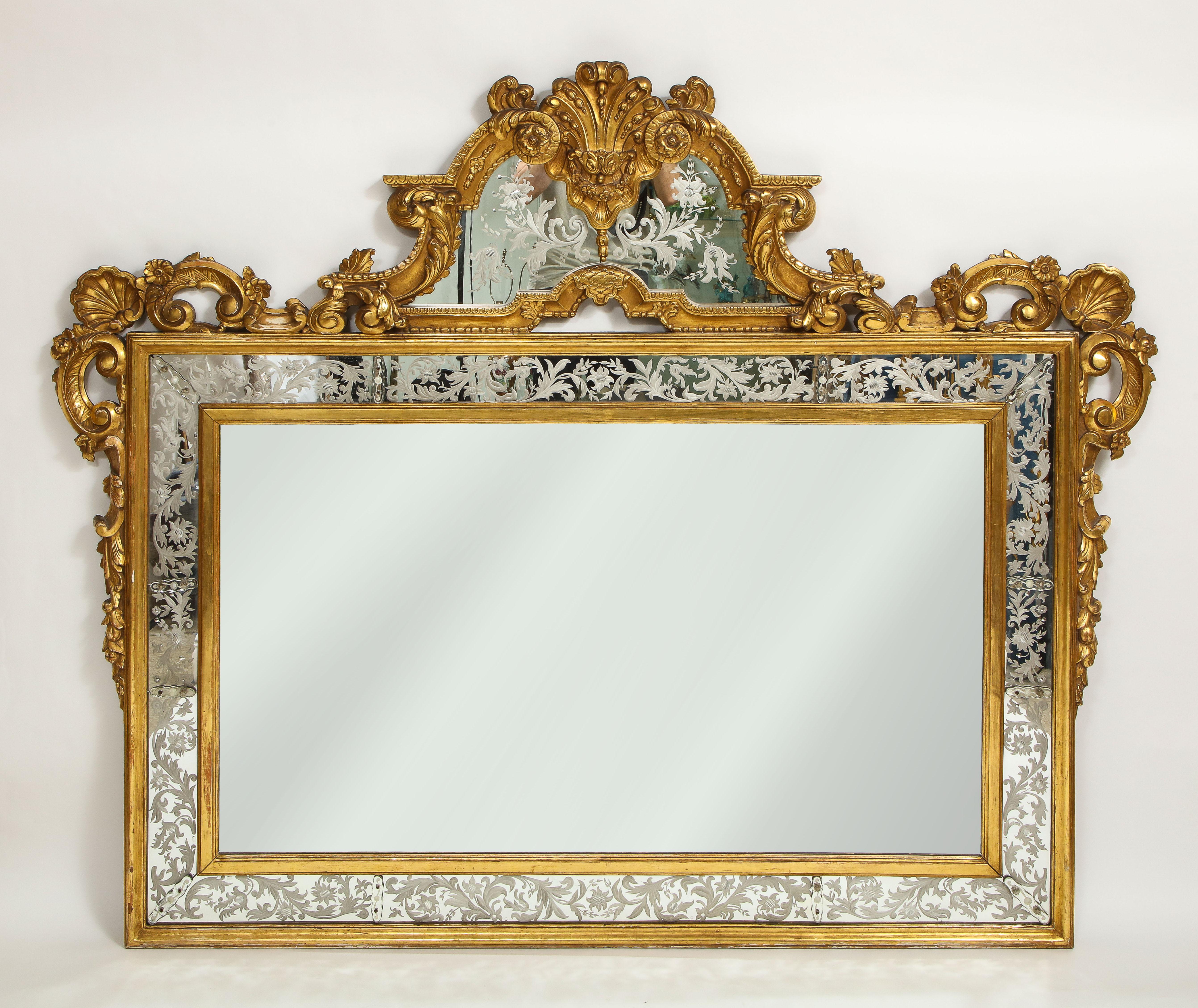 An very large and impressive Louis XVI style antique Venetian 19th century giltwood hand-etched and hand-engraved mirror. The giltwood border is all hand-carved and gilded in the finest quality 24K gold leaf. The rectangular body is hand-carved with
