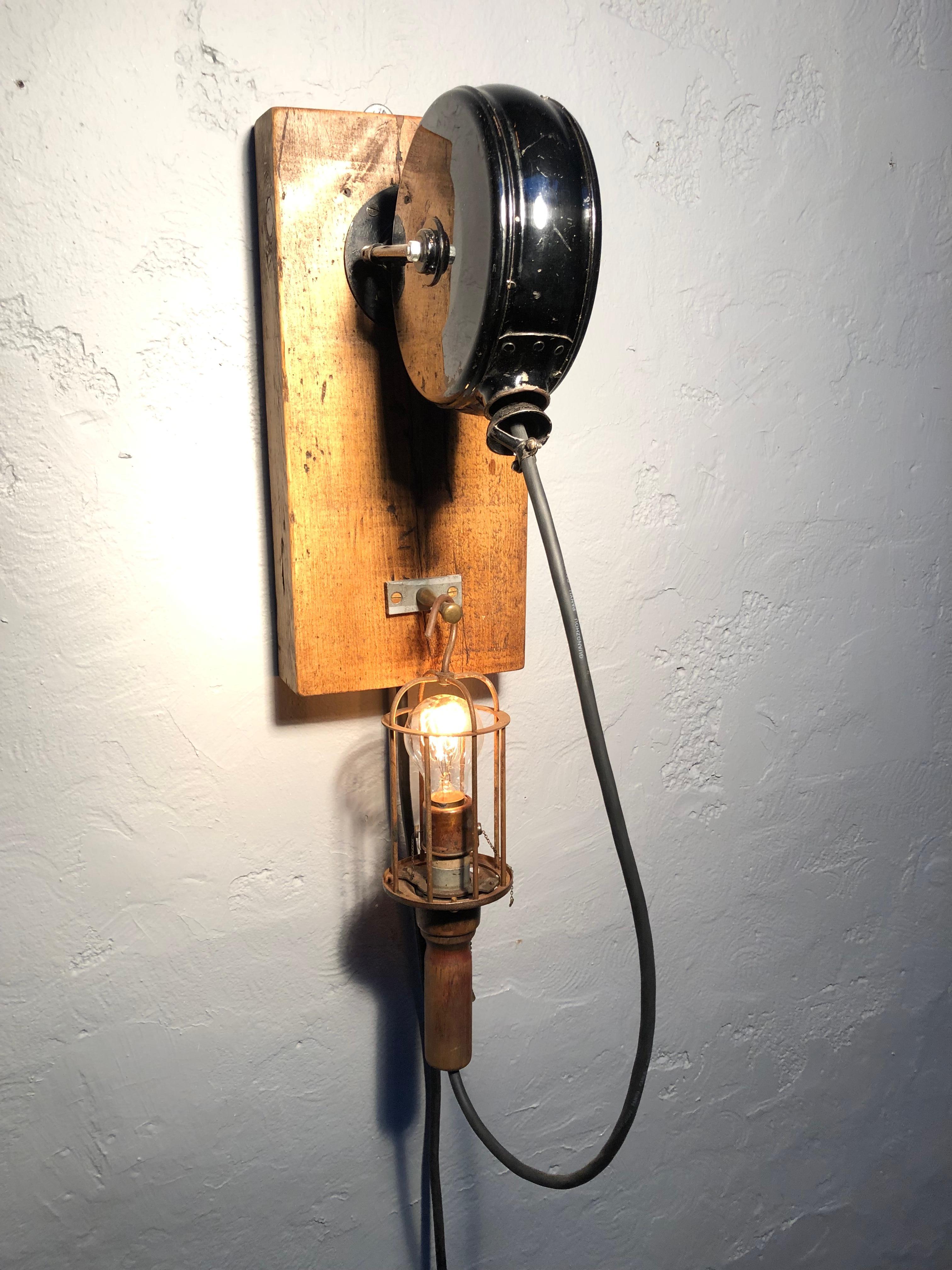An antique industrial wall mounted retractable reel work lamp.
A very cool and versatile industrial lamp. 
Fitted with an antique dimmer switch and an antique carbon filament lamp bulb. 
Wood and brass caged lamp.
Brass hanging hook. 
Pine mounting