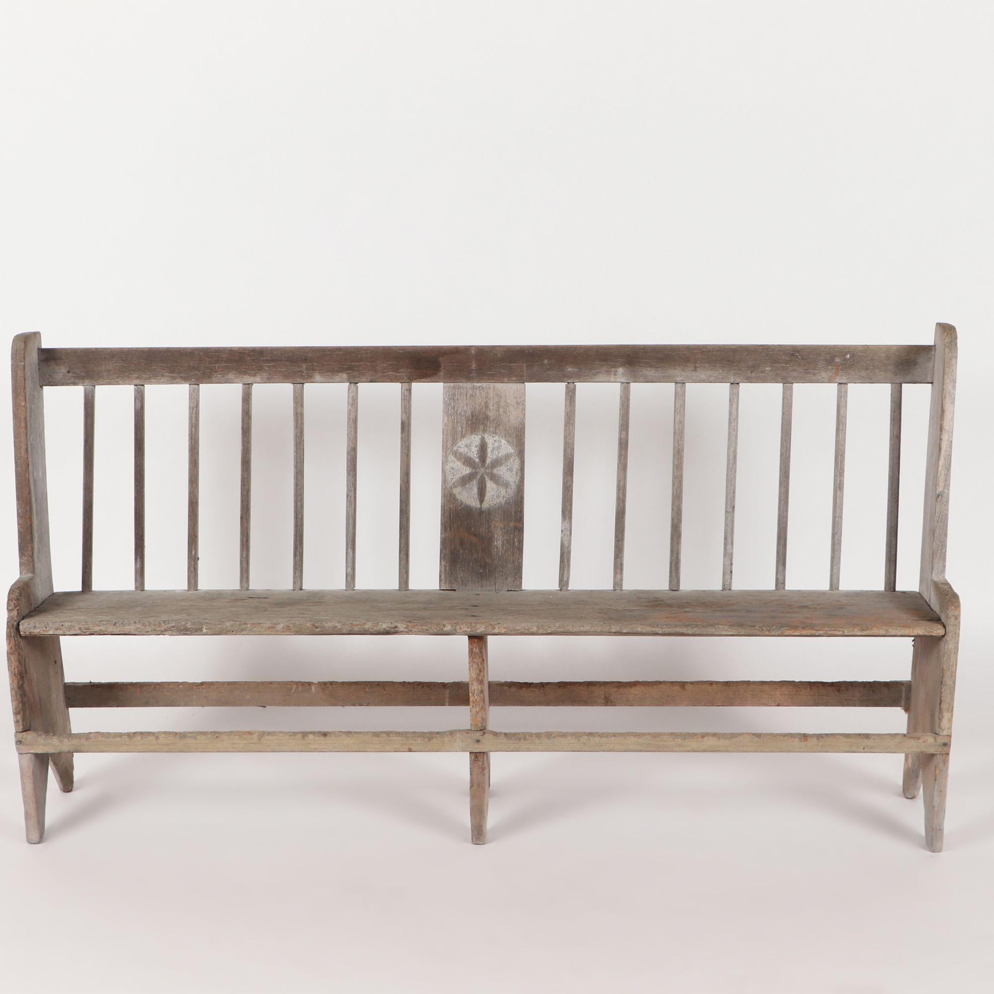 An antique bench having central hex decoration flanked by vertical rails, circa 1800.