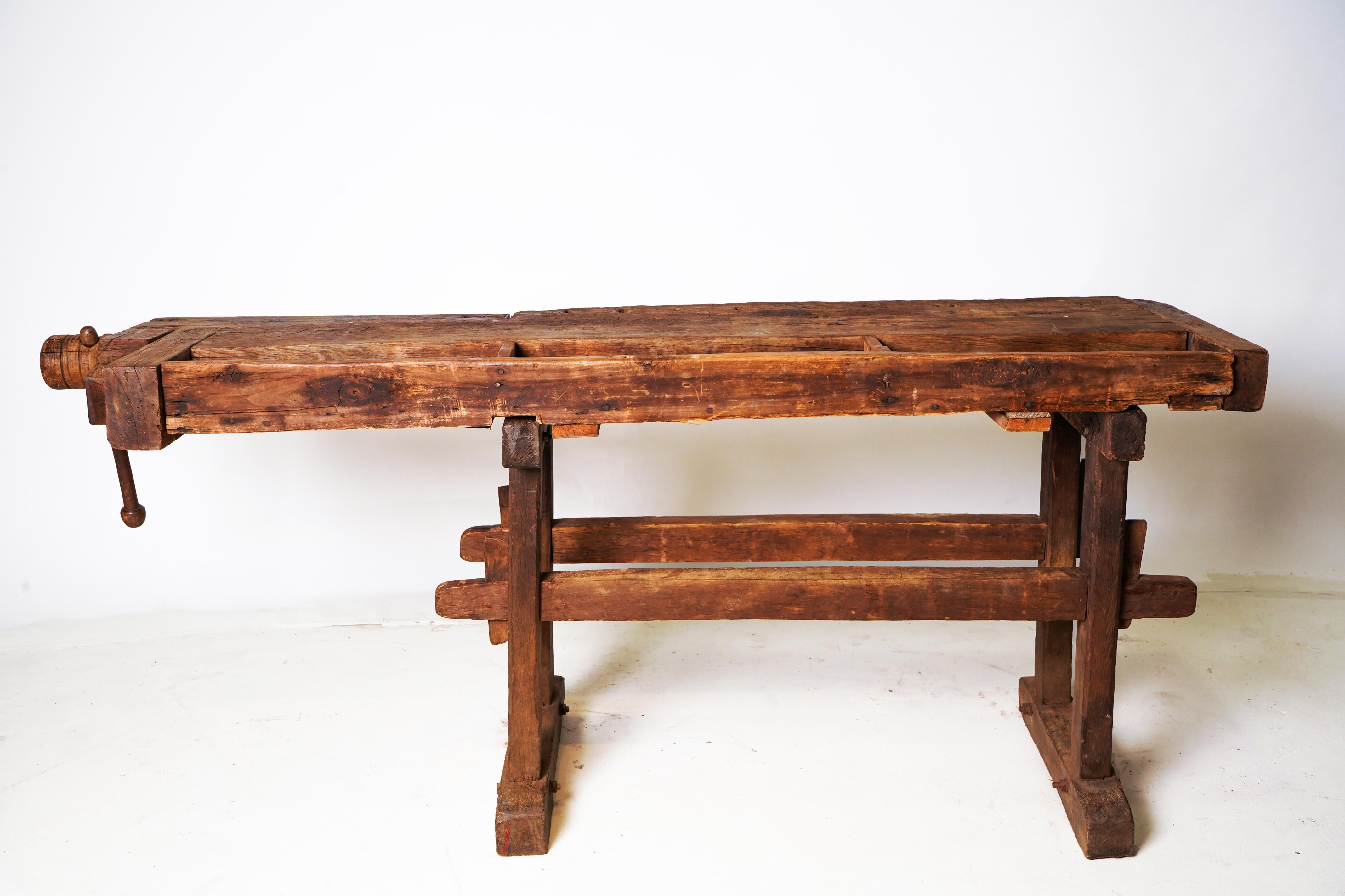 This unusually well-preserved antique workbench is made from Oak Wood and features a fully functioning vise with original working wooden screw. Remarkably for a piece that has been in such long use, all parts appear to be original. The top is
