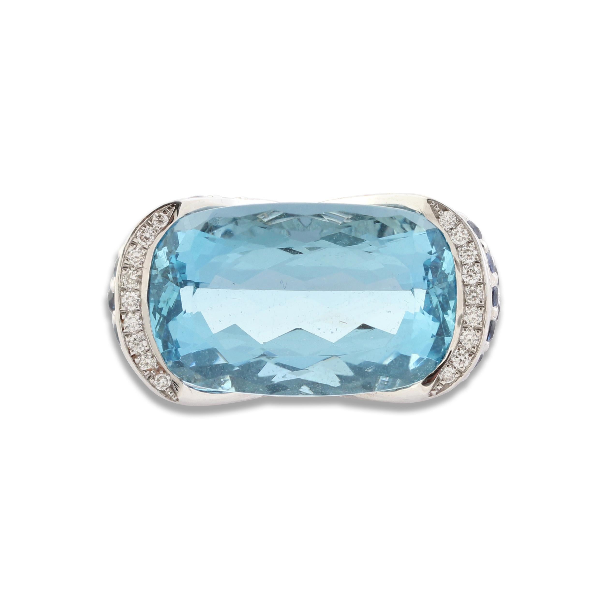 An aquamarine, sapphire & diamond cocktail ring set at the centre with a 19.90 carat cushion-cut aquamarine in an east-west setting. The mount is pavé-set with sapphires and diamonds with a deep-v cutout exposing the sides of the stone.

Ring can be